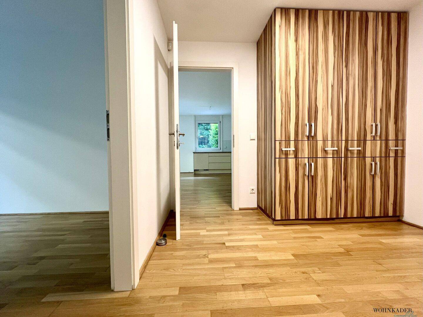 Heller Flur mit Parkettboden und einem großen Holzschrank, der zu weiteren Räumen führt.