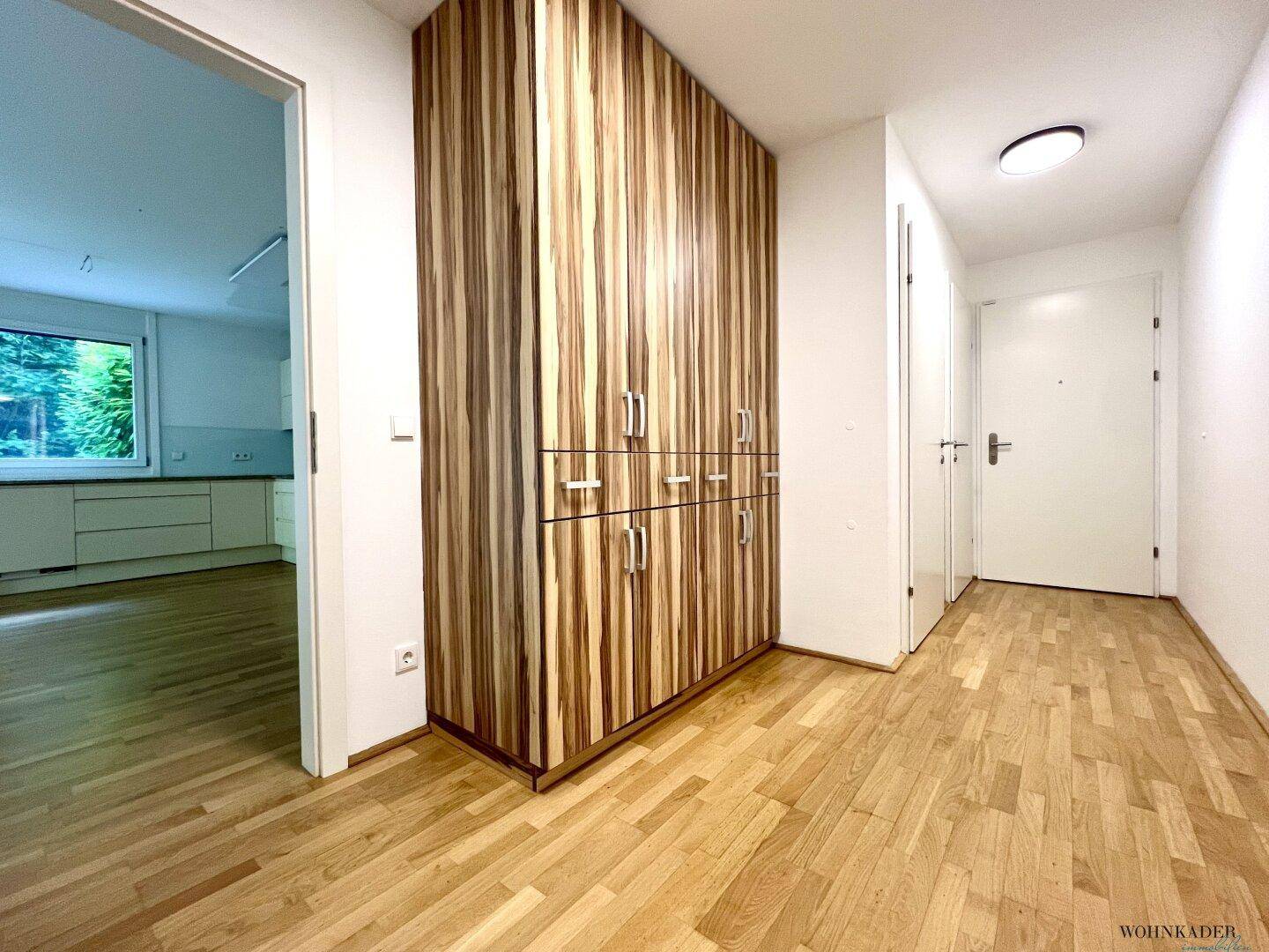Geräumiger Flur mit Parkettboden und einem großen Holzschrank, der zum Eingangsbereich führt.