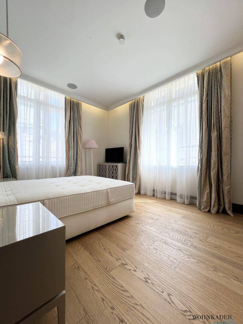 Geräumiges Schlafzimmer mit viel Tageslicht, Holzboden und eleganten Vorhängen.