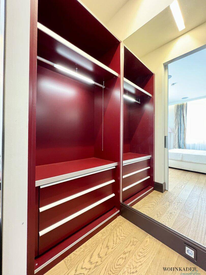 Begehbarer Kleiderschrank mit roten Einbauschränken und praktischem Holzboden.