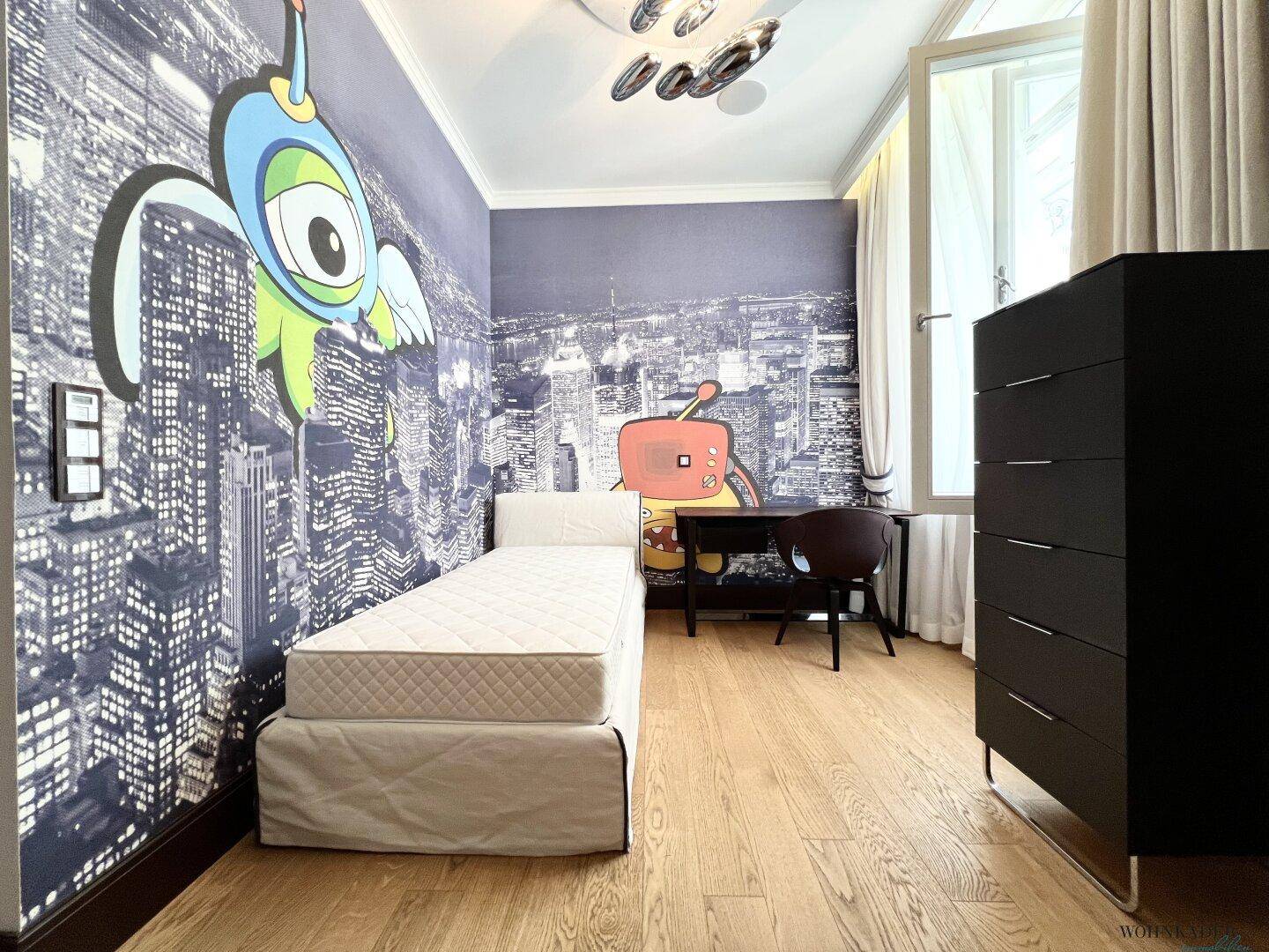 Kinderzimmer mit kreativer Wandgestaltung, Holzboden und Schreibtisch.