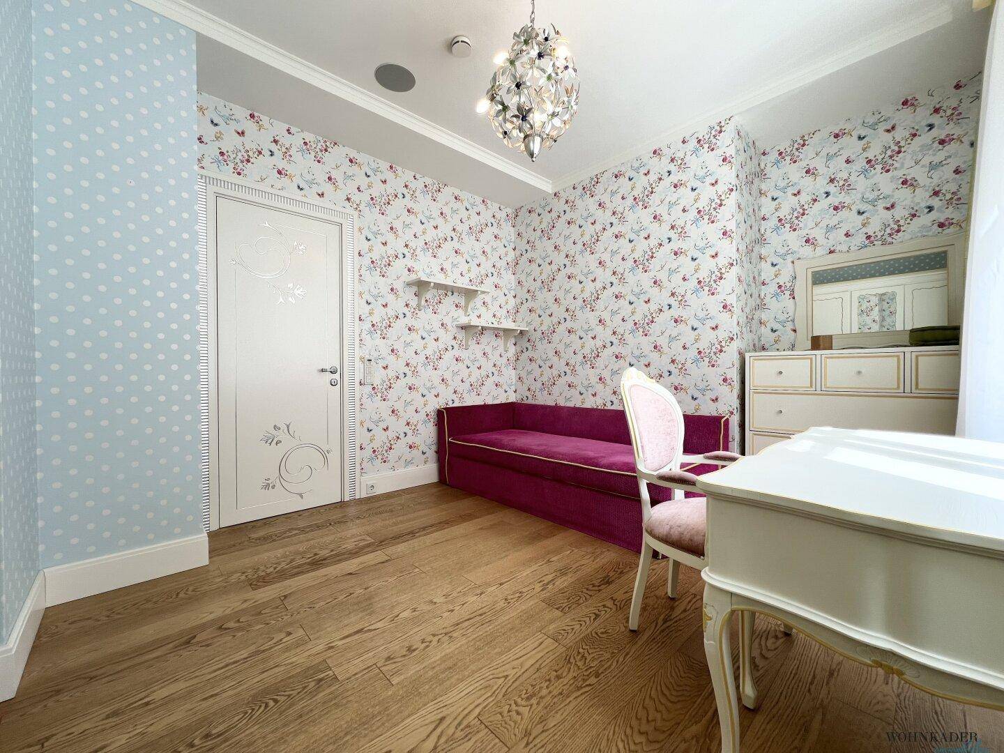 Kinderzimmer mit floraler Tapete, Holzboden und weißer Tür.
