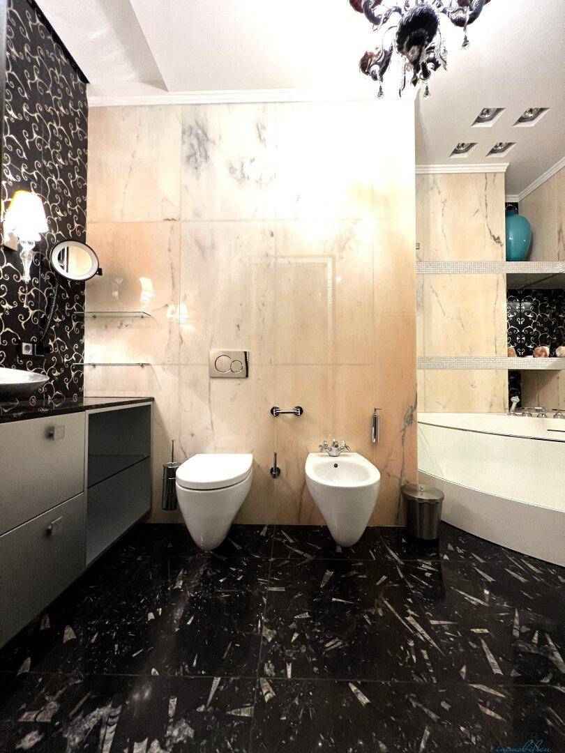 Luxuriöses Badezimmer mit schwarzem Marmorboden, Bidet und Badewanne.