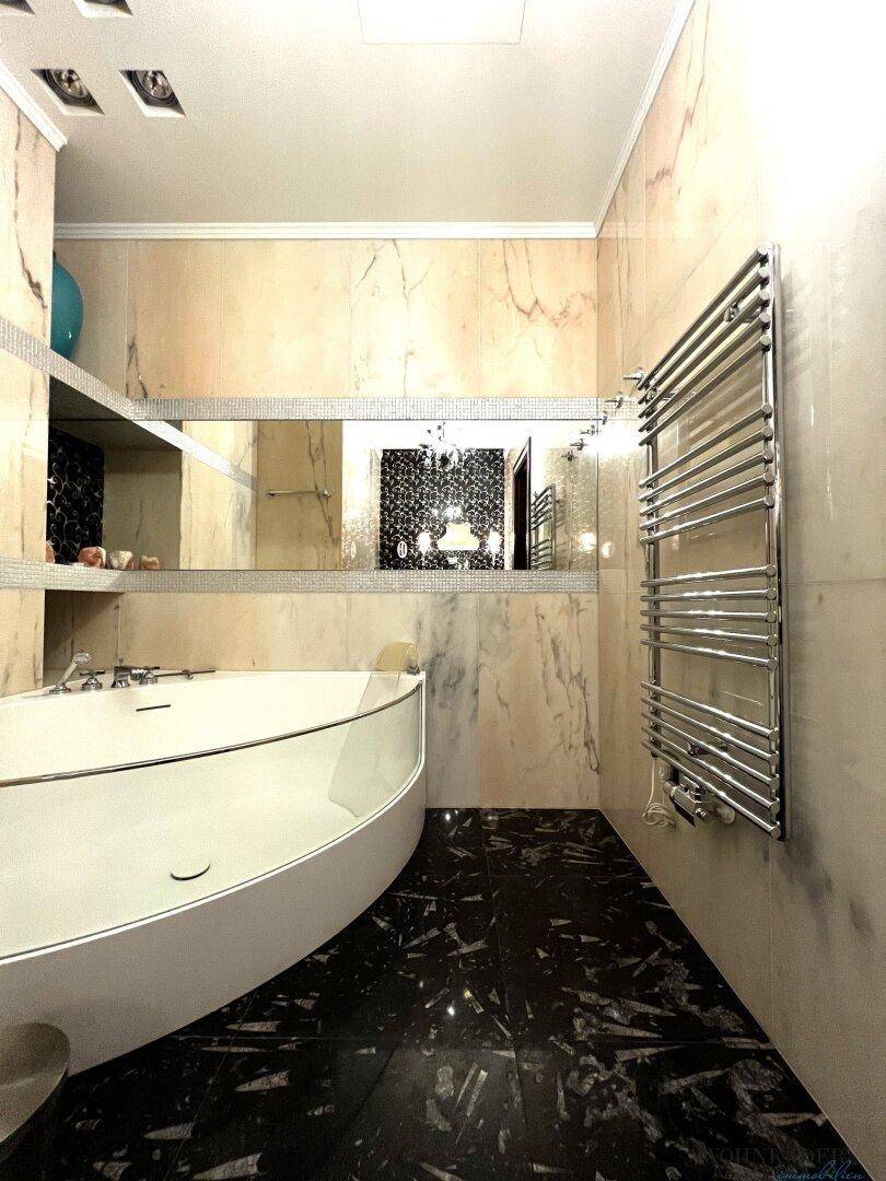 Elegantes Badezimmer mit Badewanne, beheiztem Handtuchhalter und Spiegelwand.
