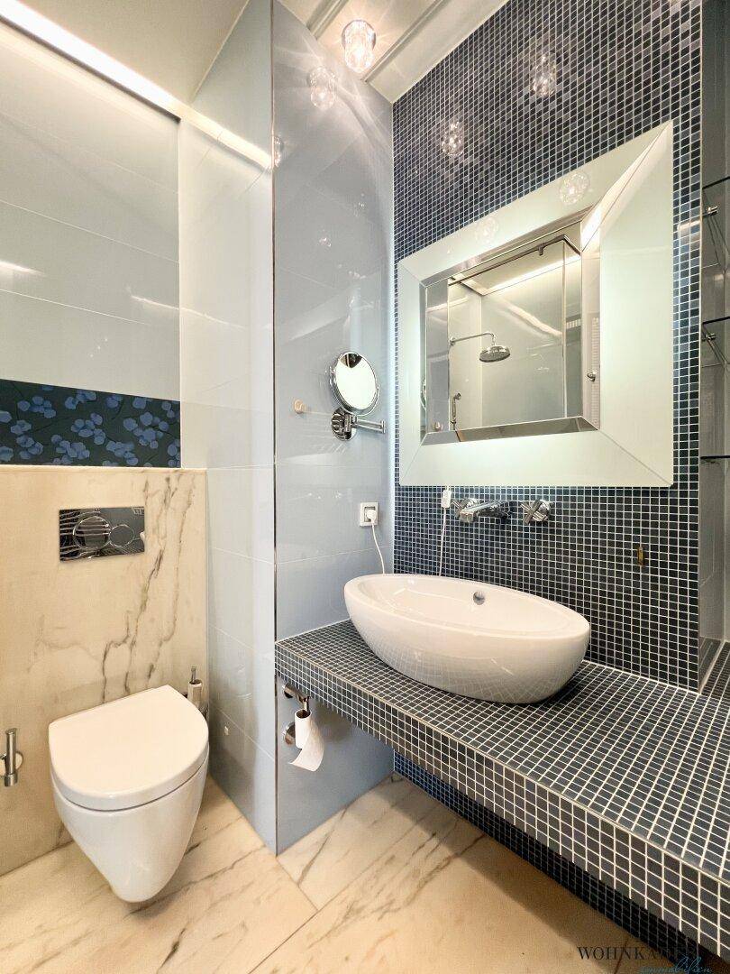 Modernes Badezimmer mit Waschtisch, Spiegel und blauen Mosaikfliesen.