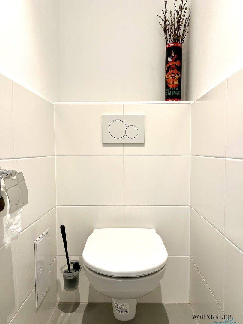 Modern gefliestes Gäste-WC mit wandhängendem WC und minimalistischem Design.