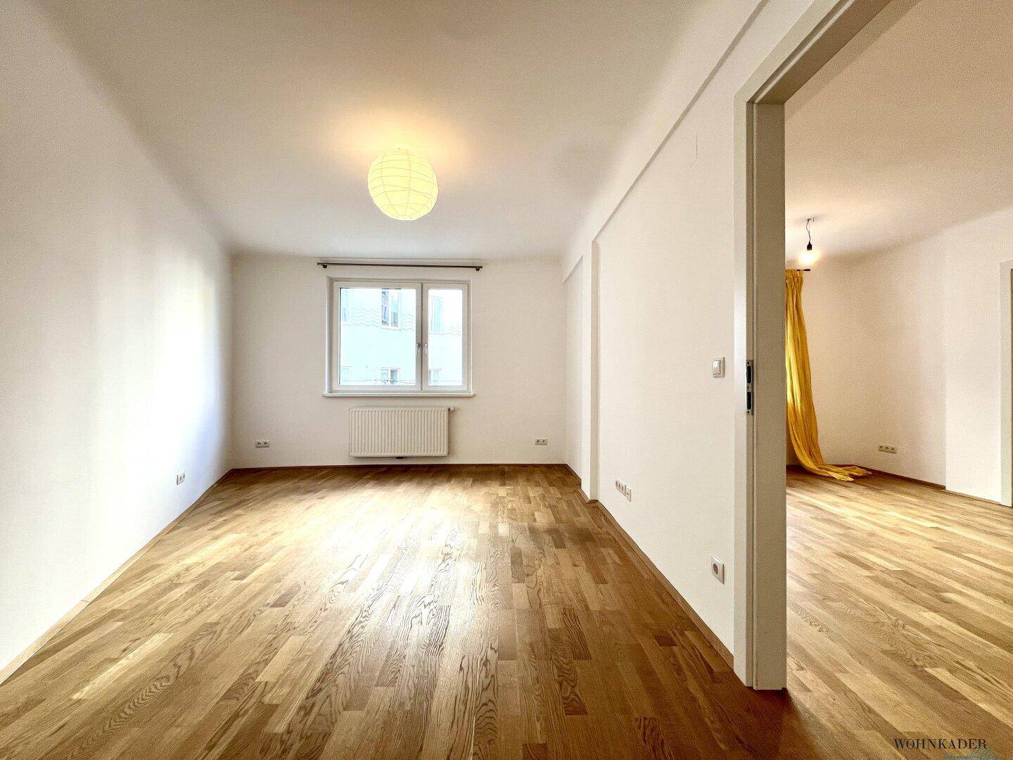 Geräumiges Zimmer mit Holzparkett und einem Fenster, das für angenehme Helligkeit sorgt.