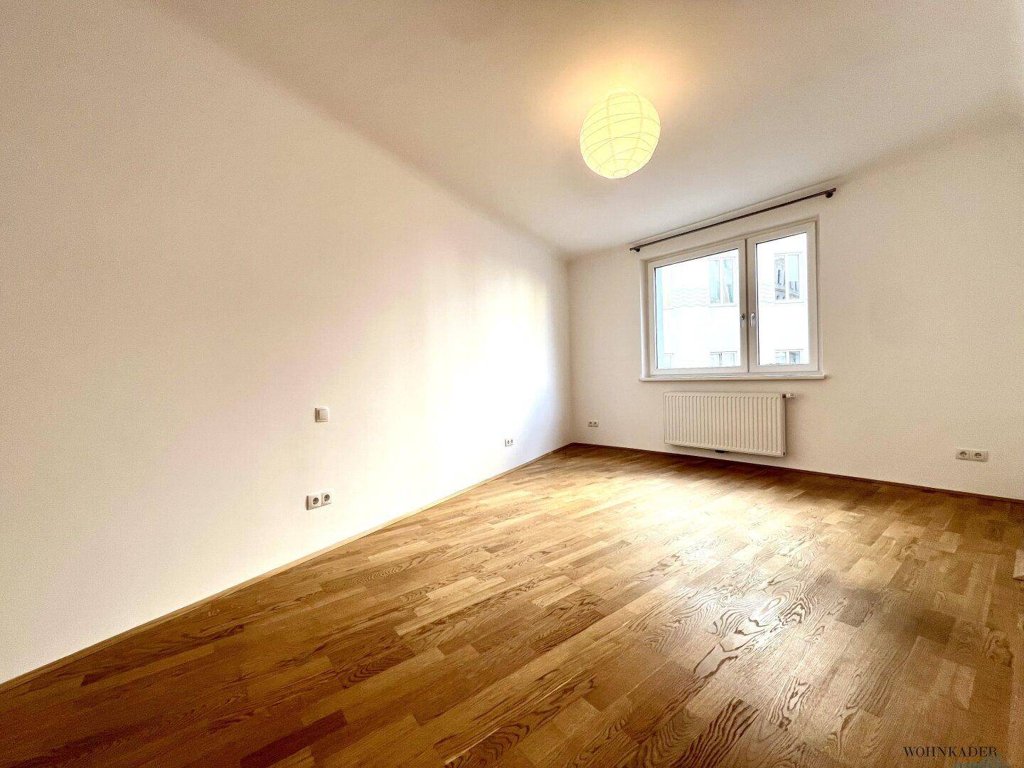 Ruhiges Schlafzimmer mit Parkettboden und einem Fenster, das viel natürliches Licht spendet.