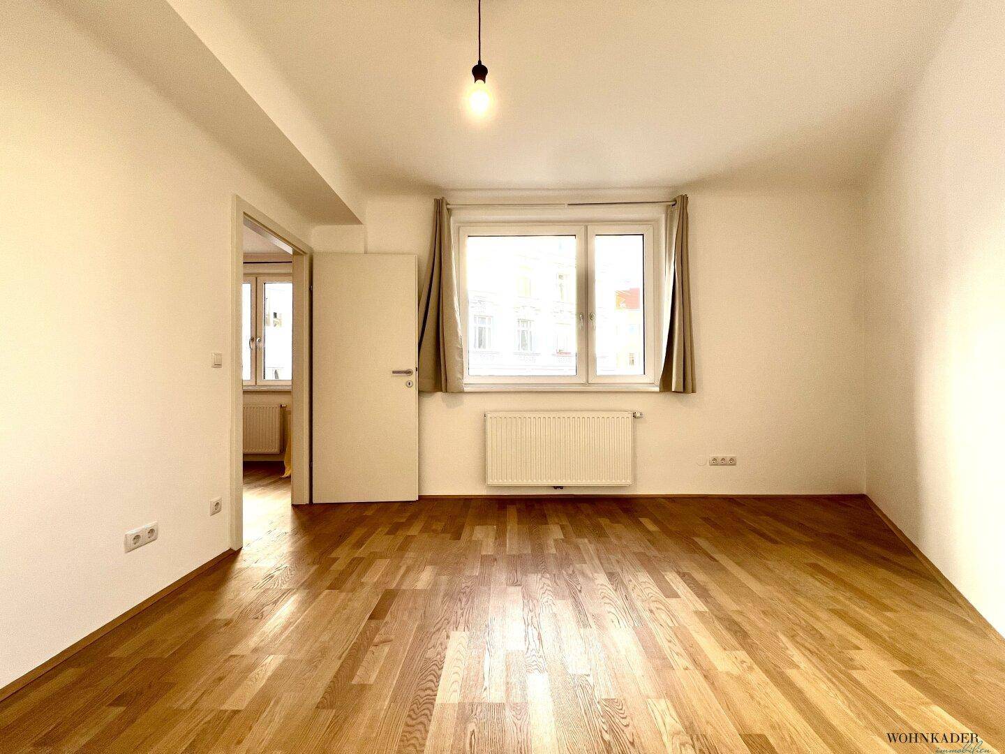 Helles Zimmer mit Parkettboden und Fenster, das einen ruhigen Rückzugsort bietet.