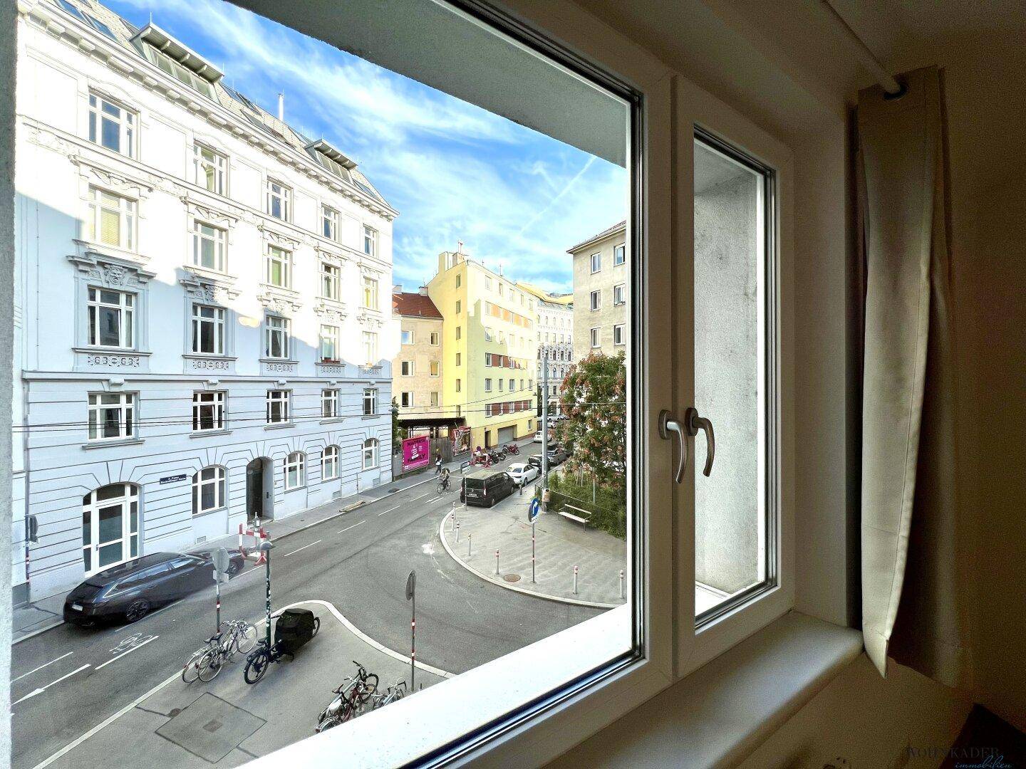 Weitblick aus dem Fenster auf die städtische Umgebung mit Gebäuden und Straßenleben.