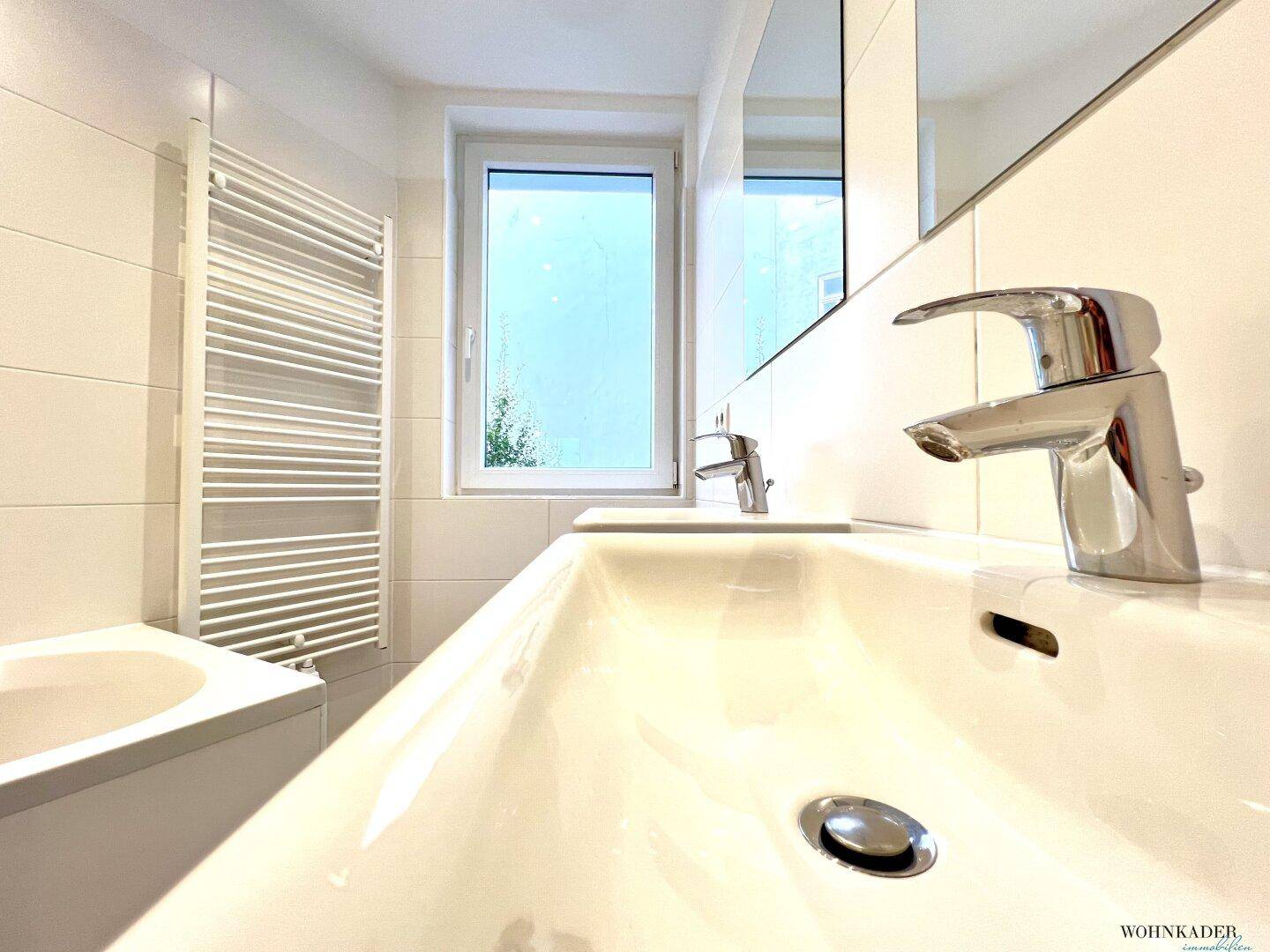 Detailansicht des Doppelwaschbeckens im modernen Badezimmer mit Fenster und Spiegel.