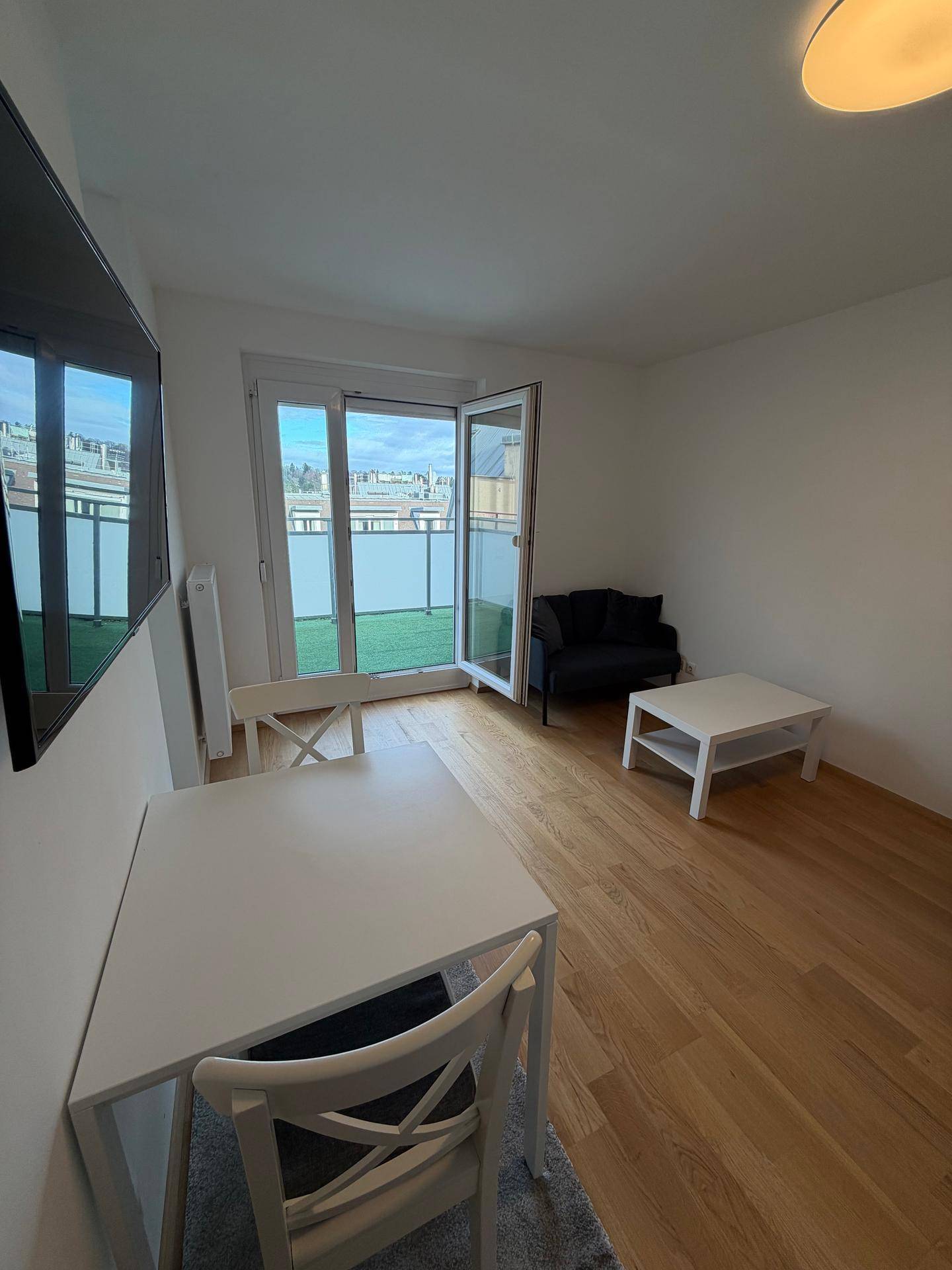 Heller Wohnbereich mit Esstisch, Sofa und direktem Zugang zum sonnigen Balkon durch große Fenster.