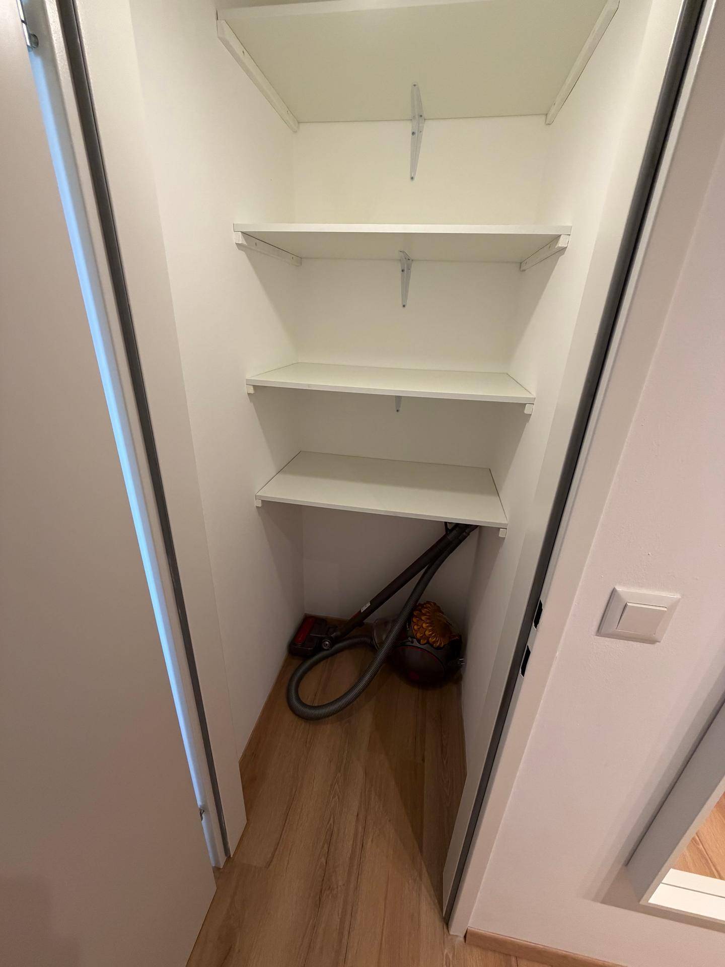 Praktischer Abstellraum mit weißen Regalen für zusätzlichen Stauraum und Laminatboden.
