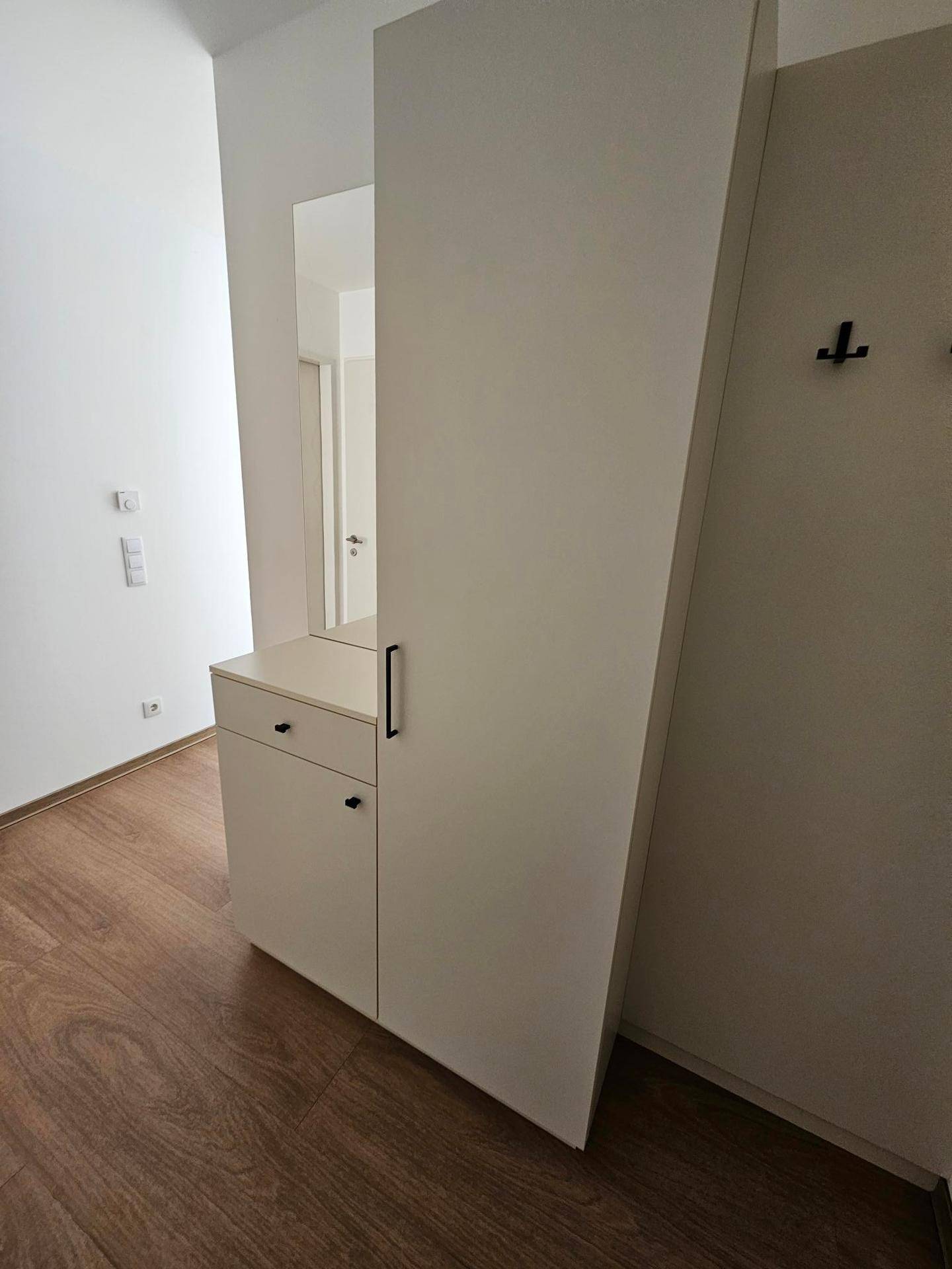 Heller Eingangsbereich mit praktischem Garderobenschrank und Spiegel.