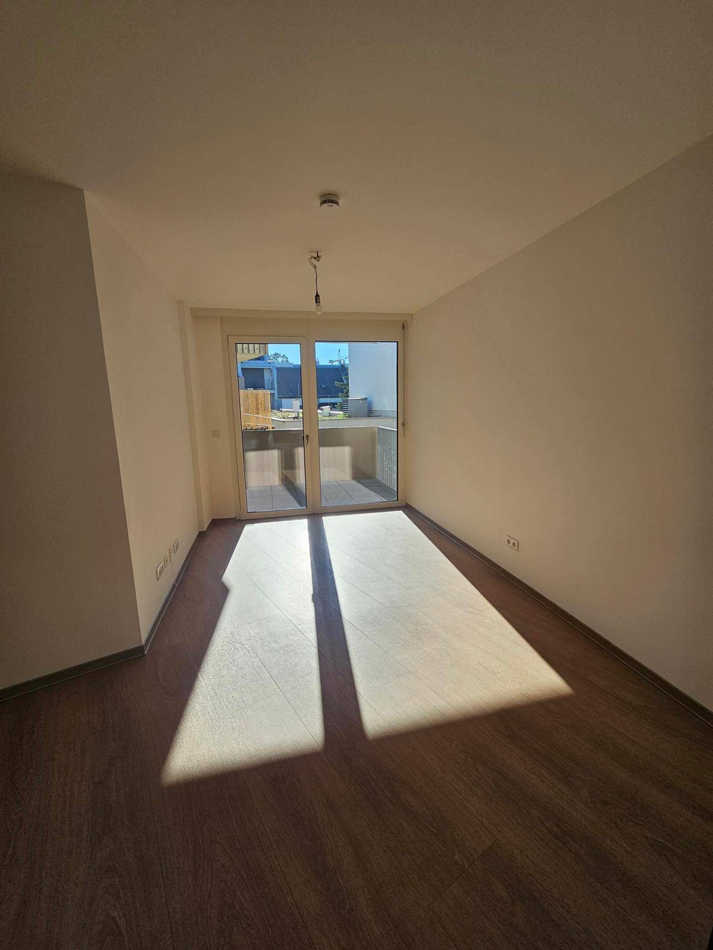 Lichtdurchfluteter Raum mit Laminatboden und großzügigem Zugang zur Terrasse.