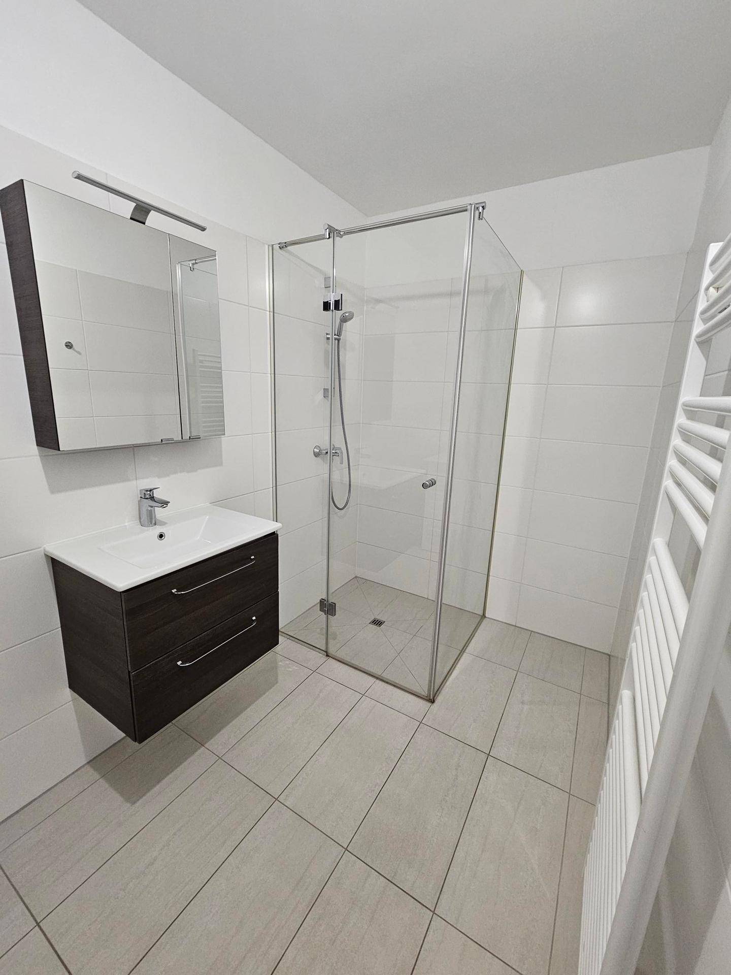 Modernes Badezimmer mit ebenerdiger Dusche, Waschtisch und Handtuchheizkörper.