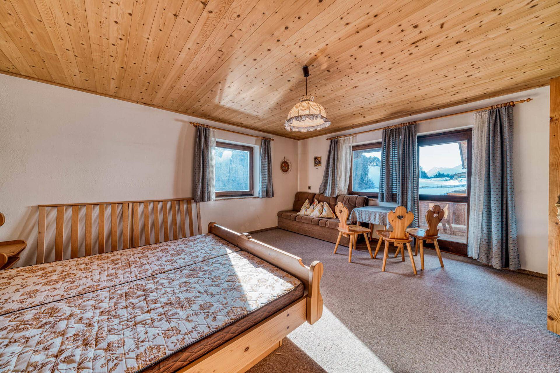Geräumiges Schlafzimmer mit Holzdecke, Teppichboden und Sitzbereich.