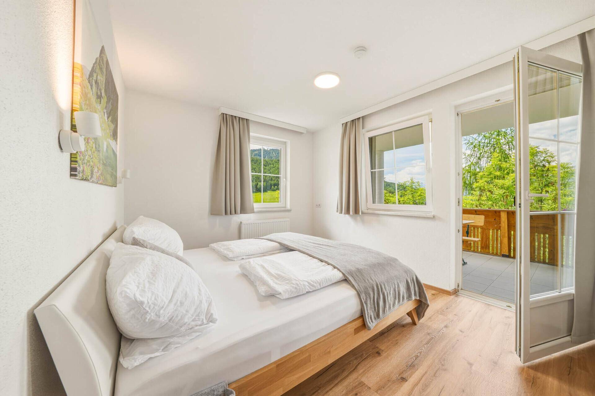 Schlafzimmer mit Balkonzugang, Holzboden und herrlichem Blick auf die Berge.