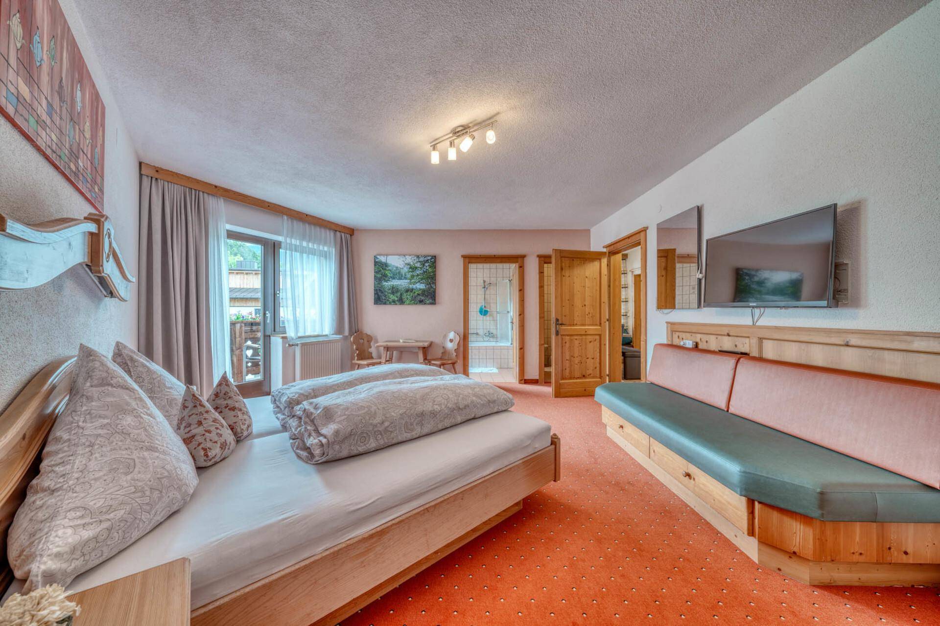 Geräumiges Schlafzimmer mit Doppelbett, Sofa und Balkonzugang.