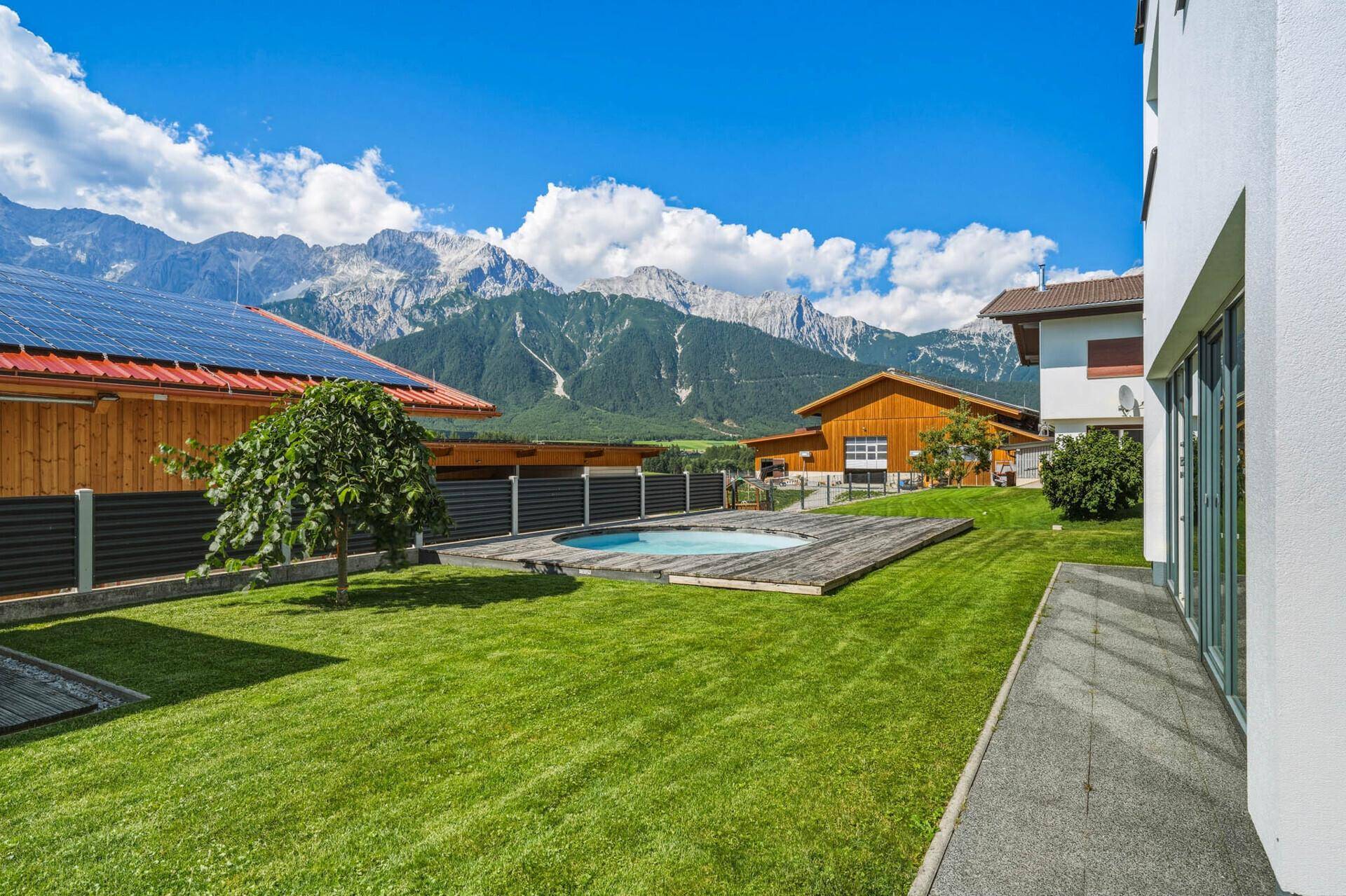 Garten mit kleinem Pool oder Whirlpool, Holzdeck und beeindruckendem Bergpanorama.