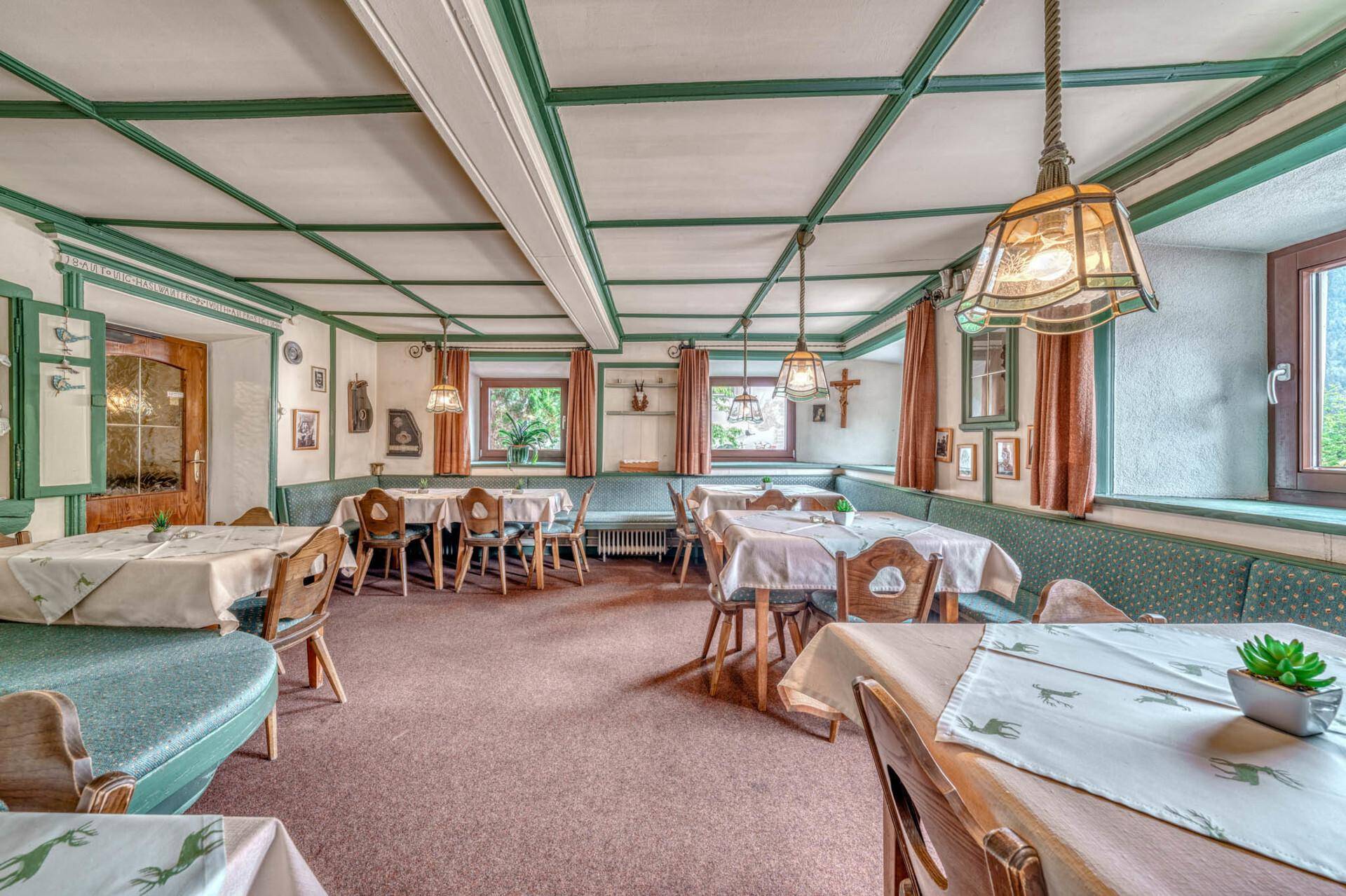 Traditioneller Speisesaal mit grünen Akzenten, Holztischen und gepolsterten Bänken.