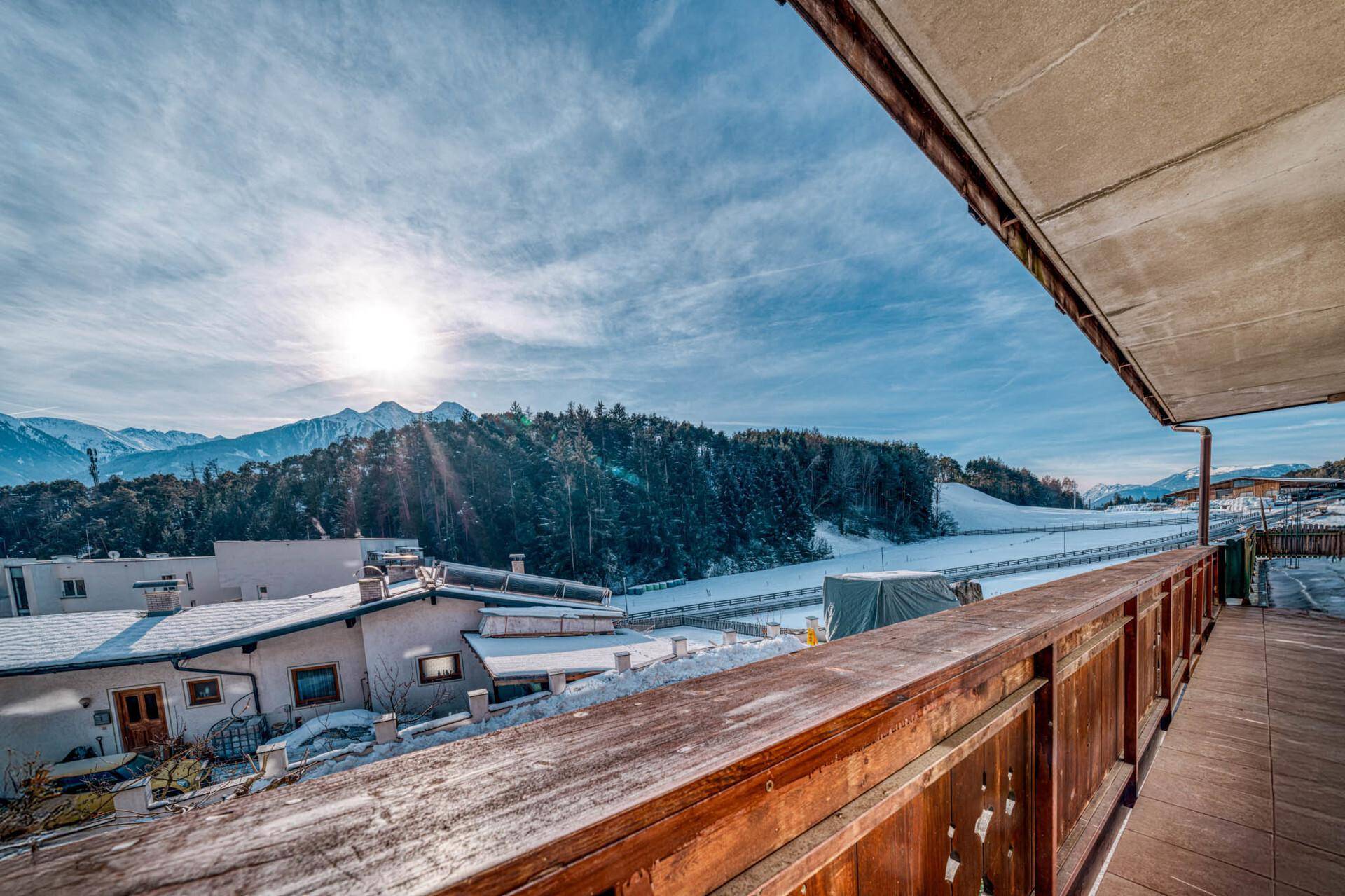 Breiter Holzbalkon mit Blick auf die verschneite Natur und die Bergkulisse.