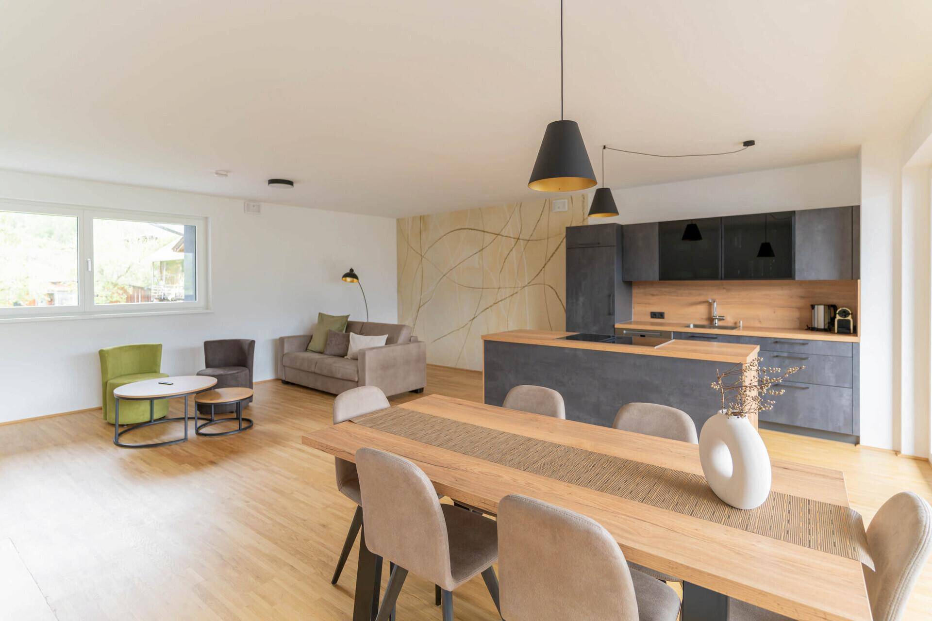 Heller Wohn-Essbereich mit offener Küche, Holzboden und dekorativer Wandgestaltung.