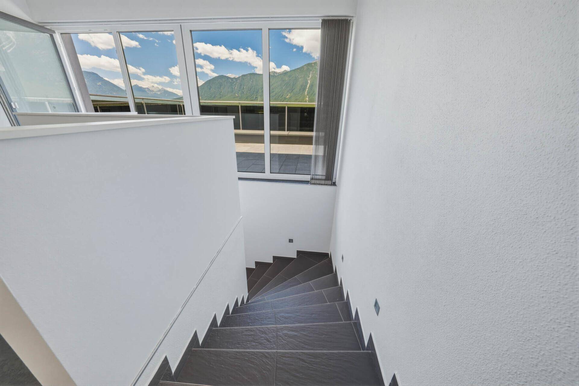 Treppenabgang mit großen Fenstern, die viel Licht hereinlassen und einen weiten Blick bieten.
