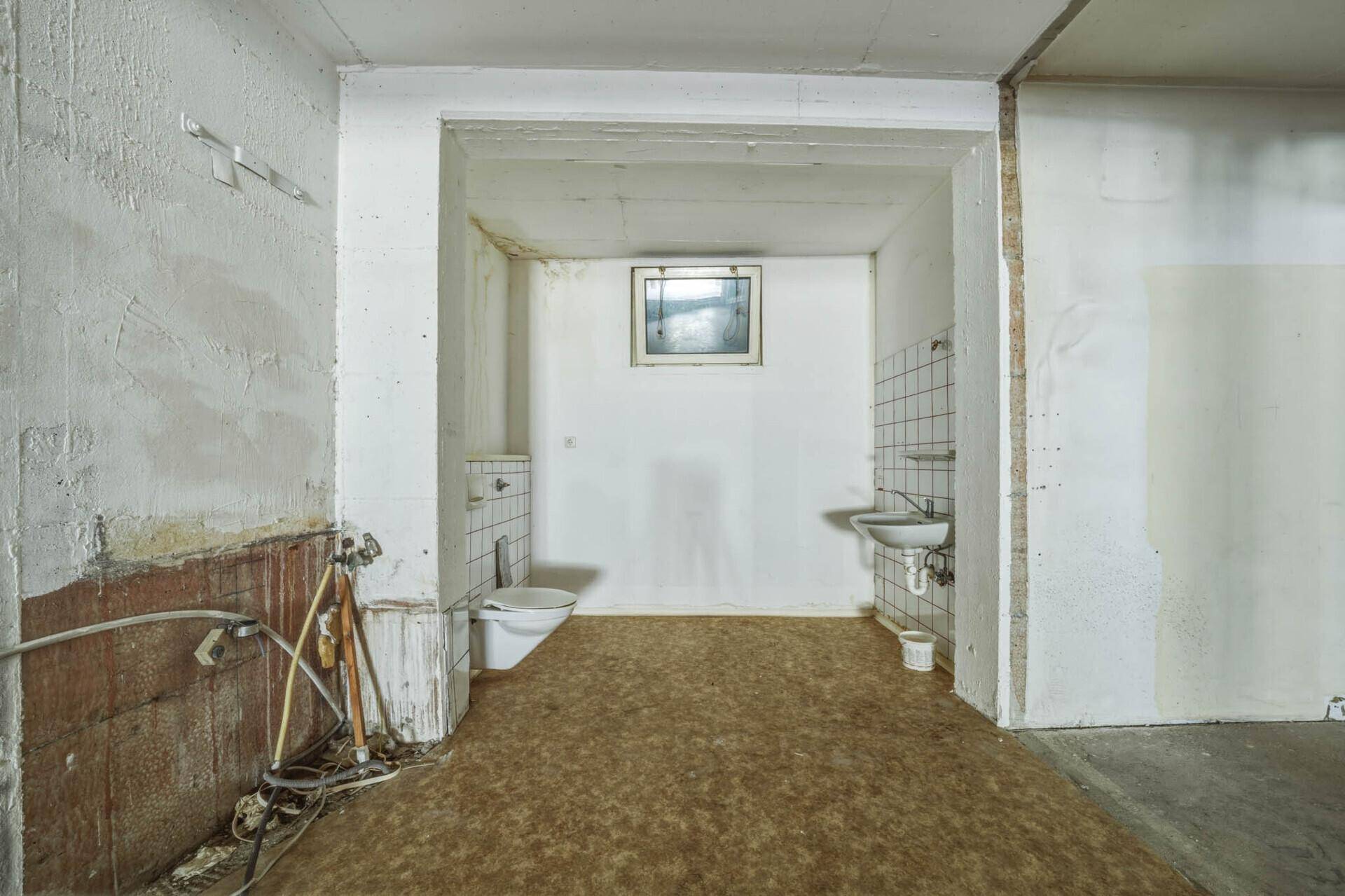 Einfache Gästetoilette im Untergeschoss mit Fenster, WC und Waschbecken, renovierungsbedürftig.