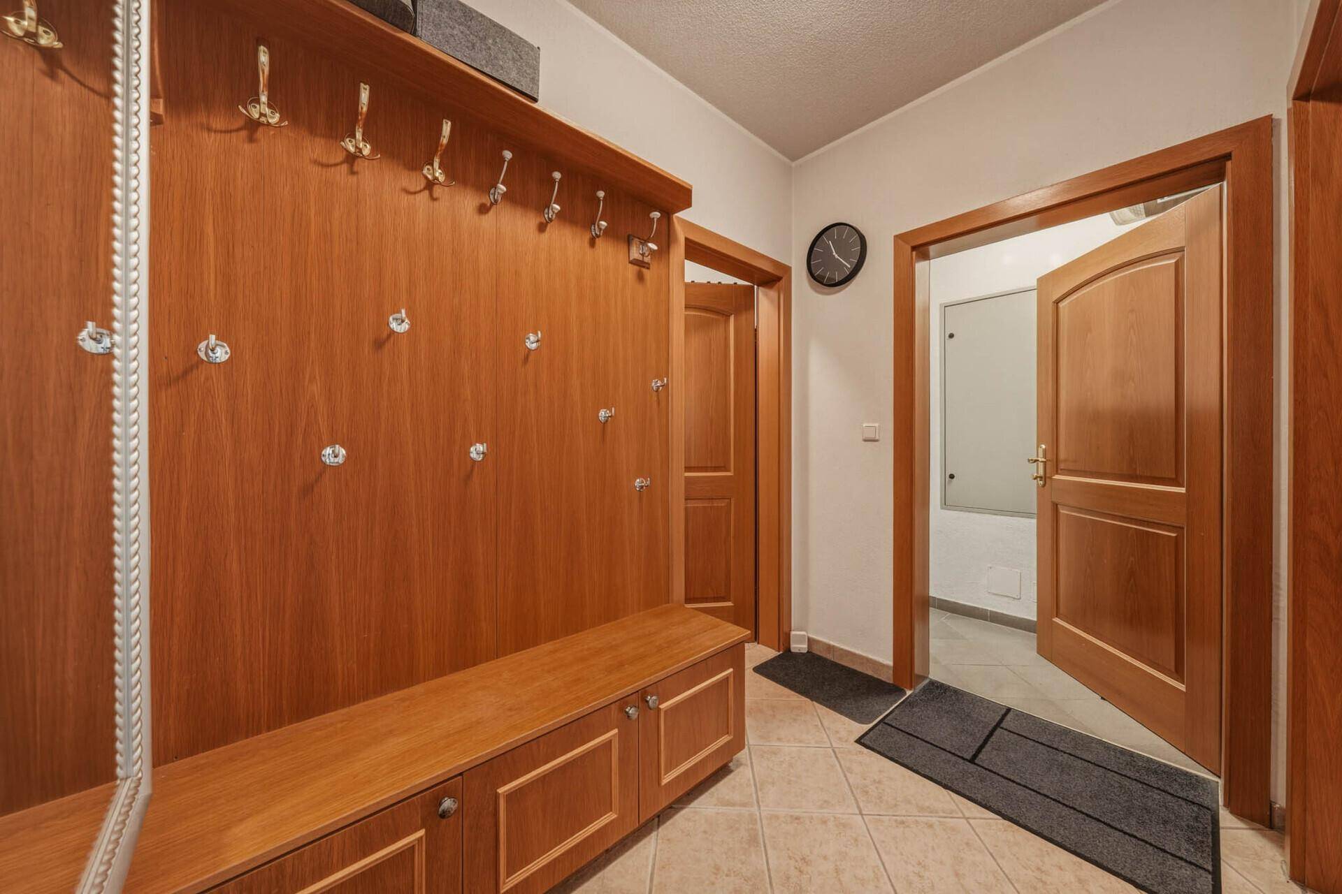Praktischer Flur mit Holzgarderobe, Sitzbank und Zugang zu weiteren Räumen.
