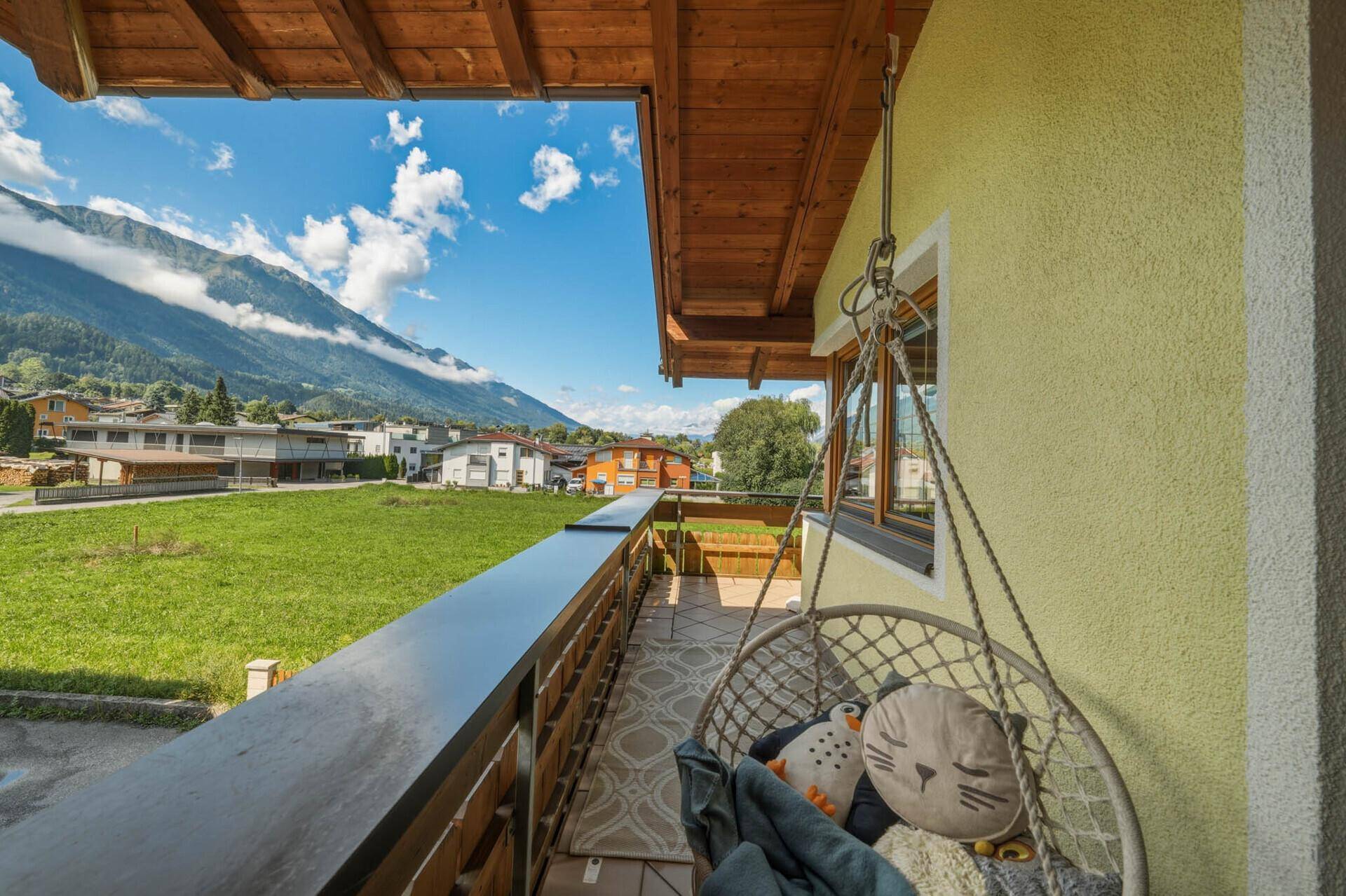 Langer Balkon mit Hängesessel und weitem Blick auf die Berge und Wiesen.