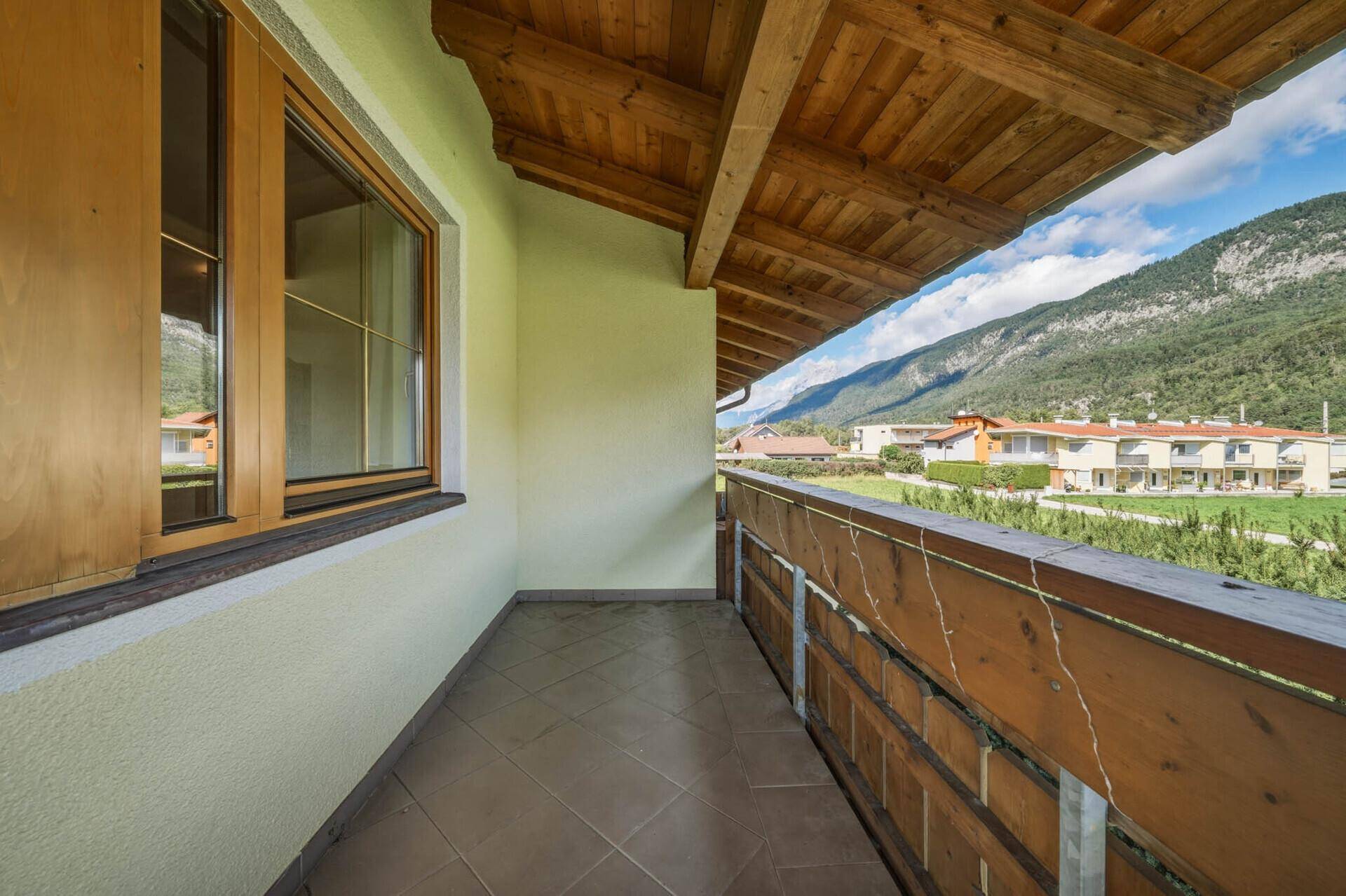 Überdachter Balkon mit Fliesenboden und Bergblick, ideal zum Entspannen.