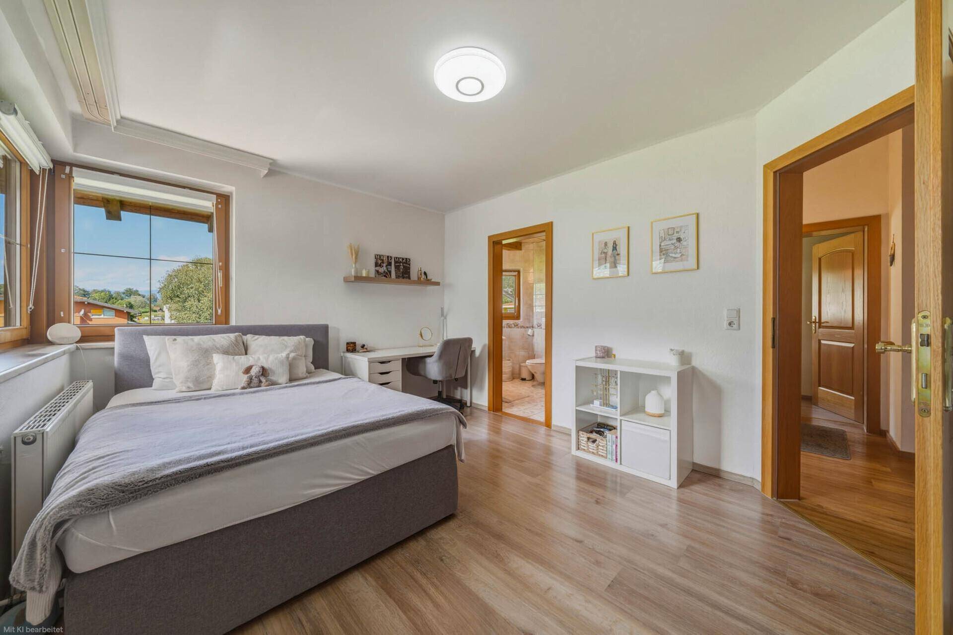 Schlafzimmer mit Bett, Schreibtisch und Blick auf die umliegende Natur.