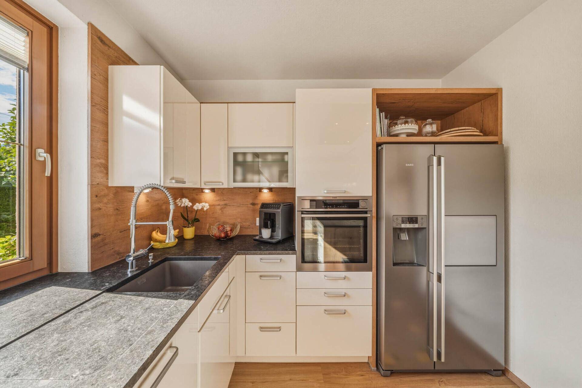 Hochwertige Küche mit integriertem Kühlschrank, Backofen und dunkler Arbeitsplatte.