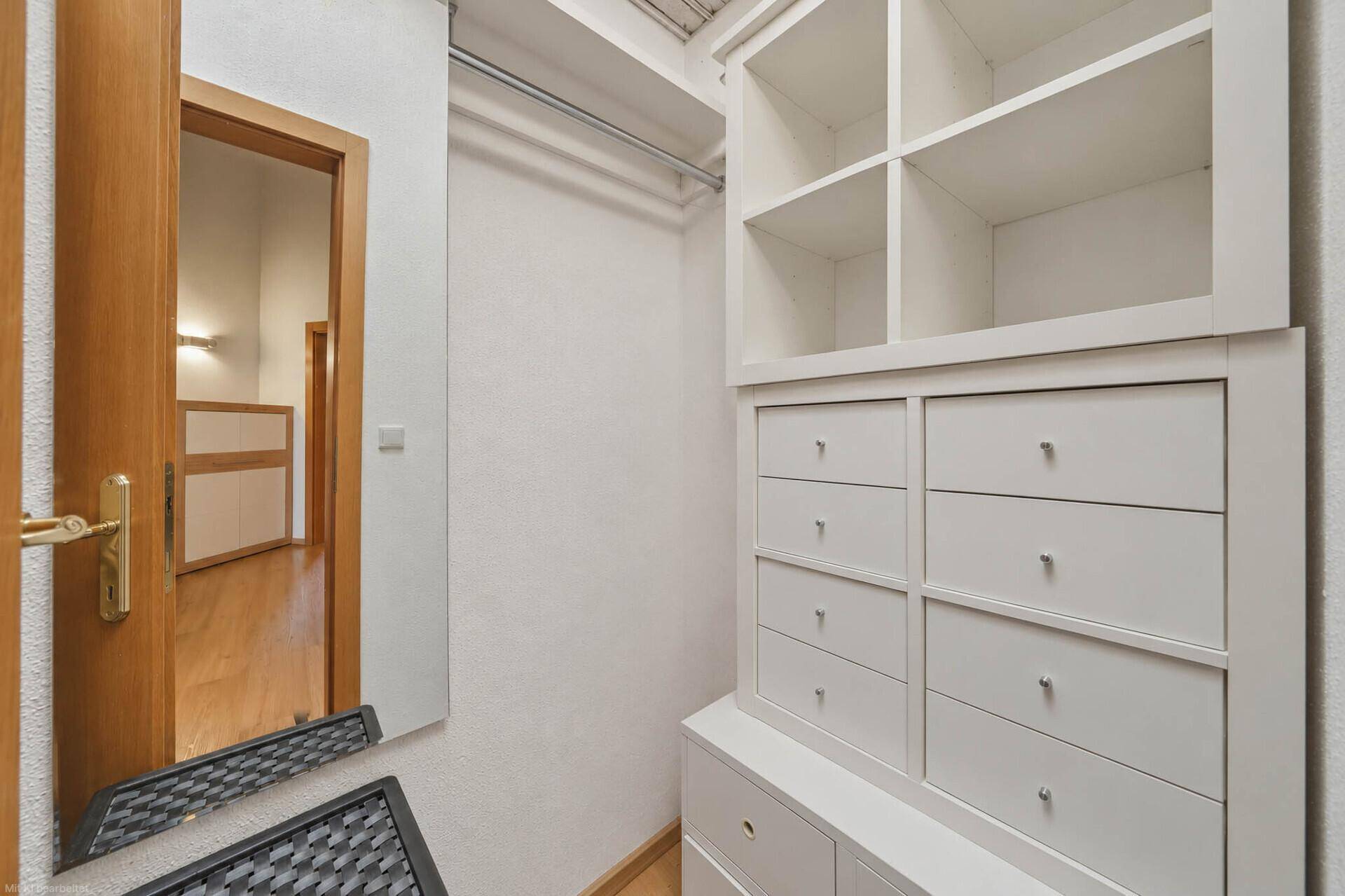 Begehbarer Kleiderschrank mit weißen Regalen und Schubladen, ideal für zusätzlichen Stauraum.