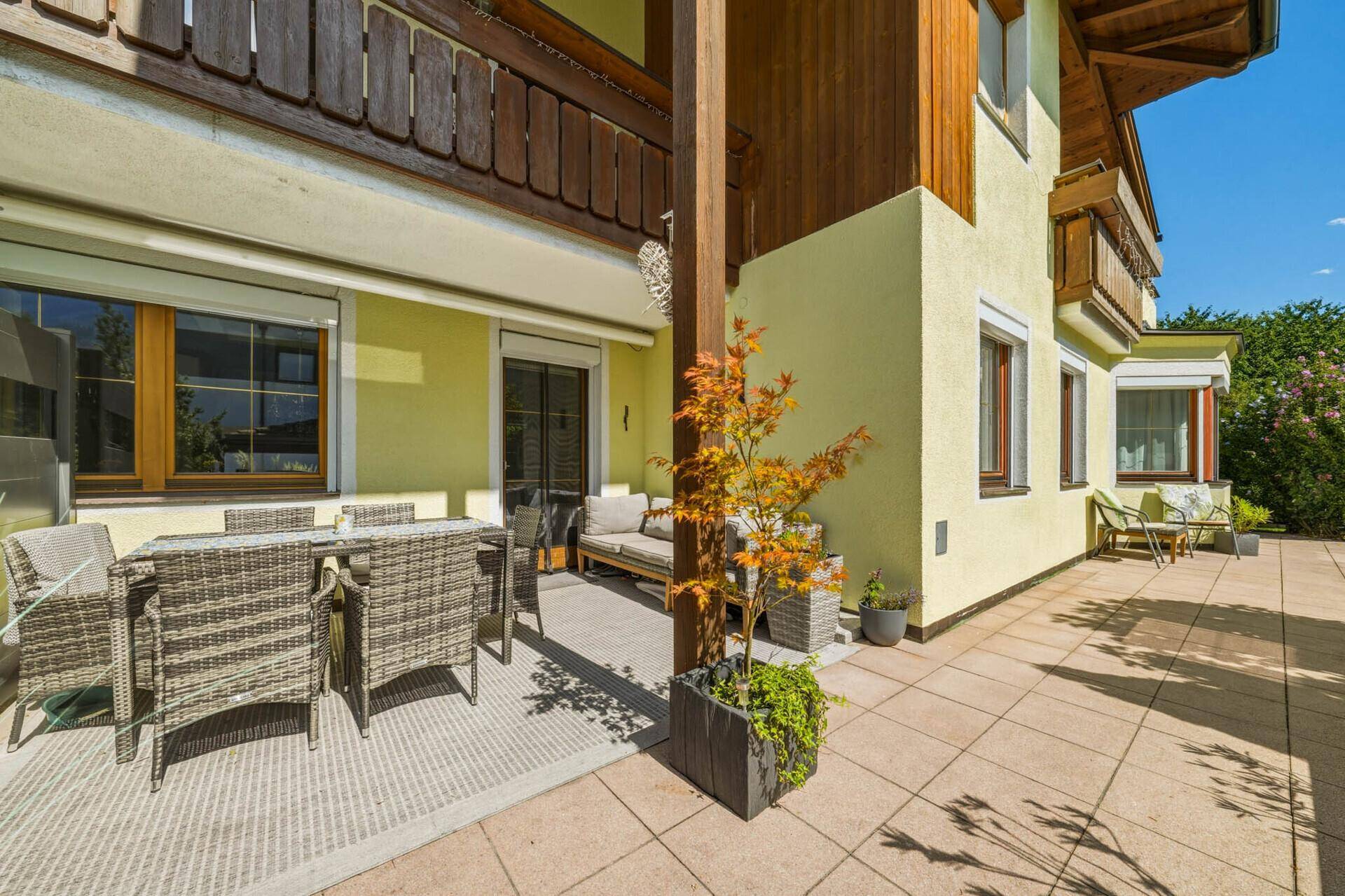 Großzügige Terrasse mit Rattanmöbeln und Fliesenboden, ideal für entspannte Stunden im Freien.