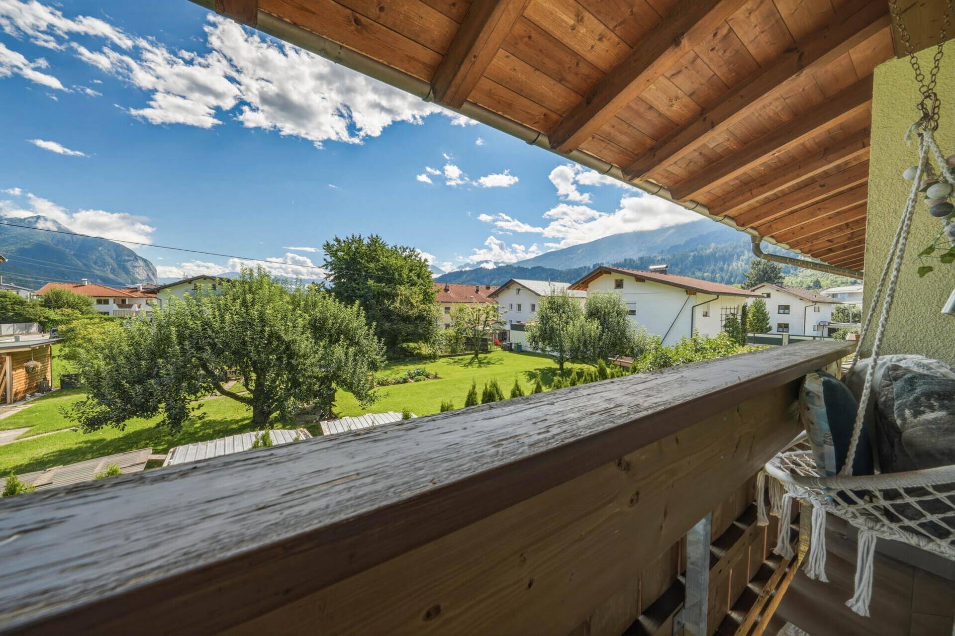 Sonniger Balkon mit Hängesessel und Panoramablick auf die grüne Umgebung.