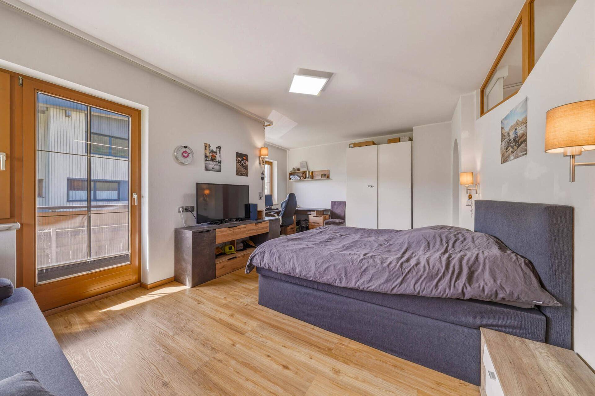 Schlafzimmer mit Doppelbett, Sofa und Balkonzugang, hell und freundlich.