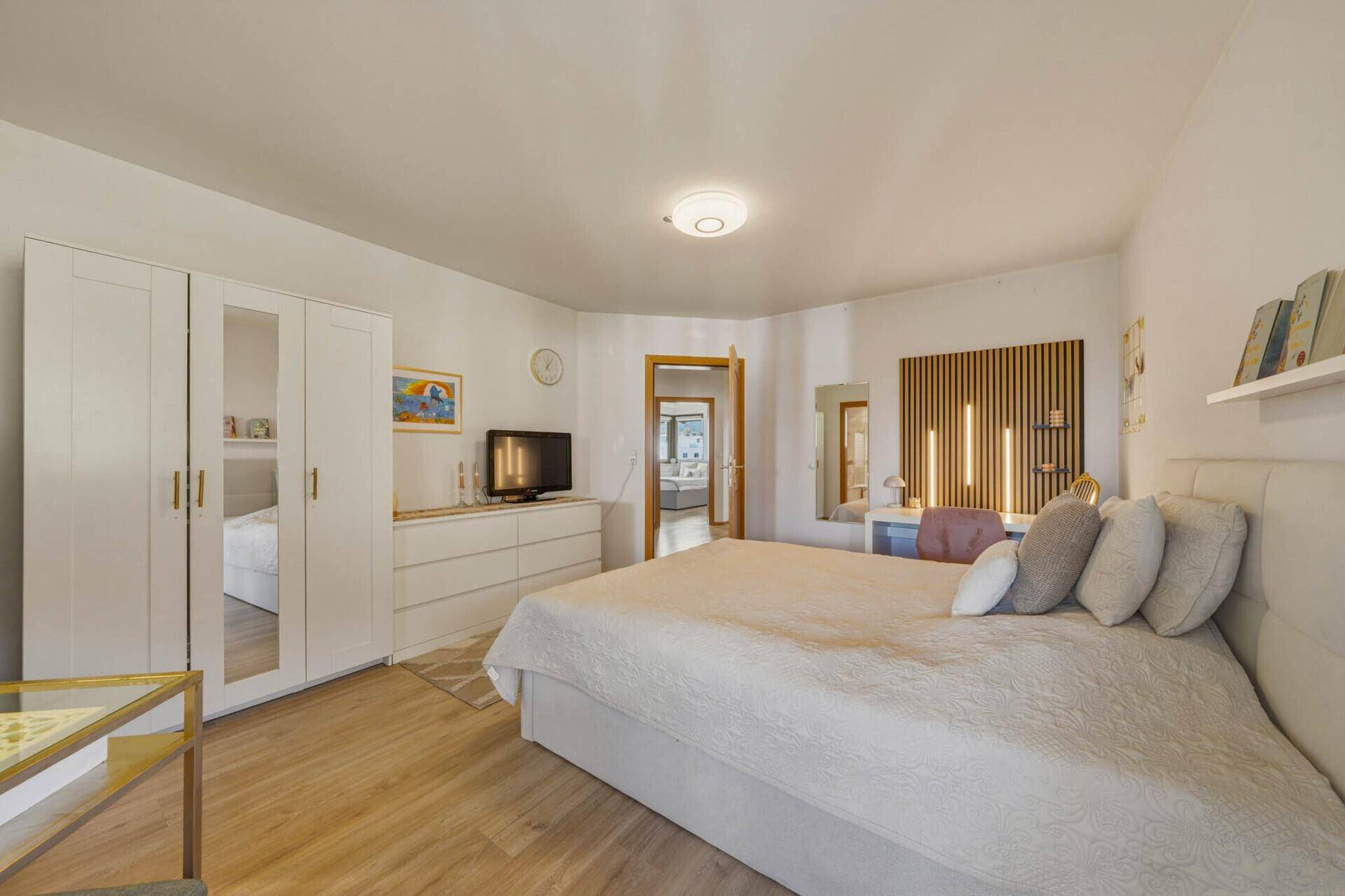 Helles Schlafzimmer mit Doppelbett, weißem Kleiderschrank und Holzboden.