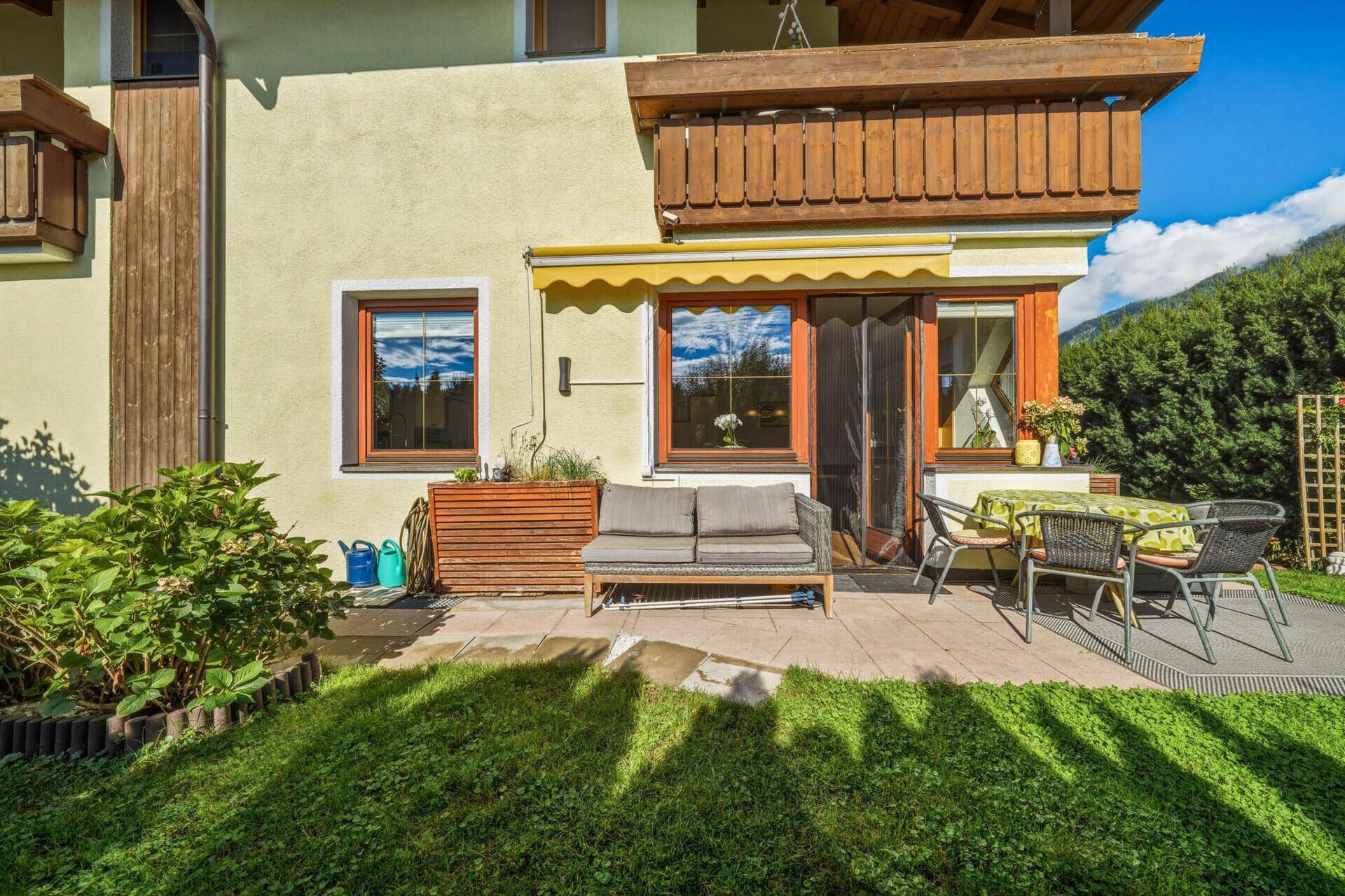 Gemütliche Terrasse mit Sitzgruppe und Blick auf den gepflegten Garten und die umliegende Natur.