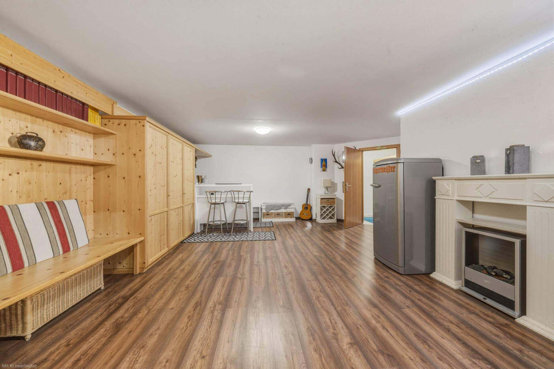 Vielseitiger Raum im Untergeschoss mit Holzboden, Einbauschränken und einer kleinen Bar.
