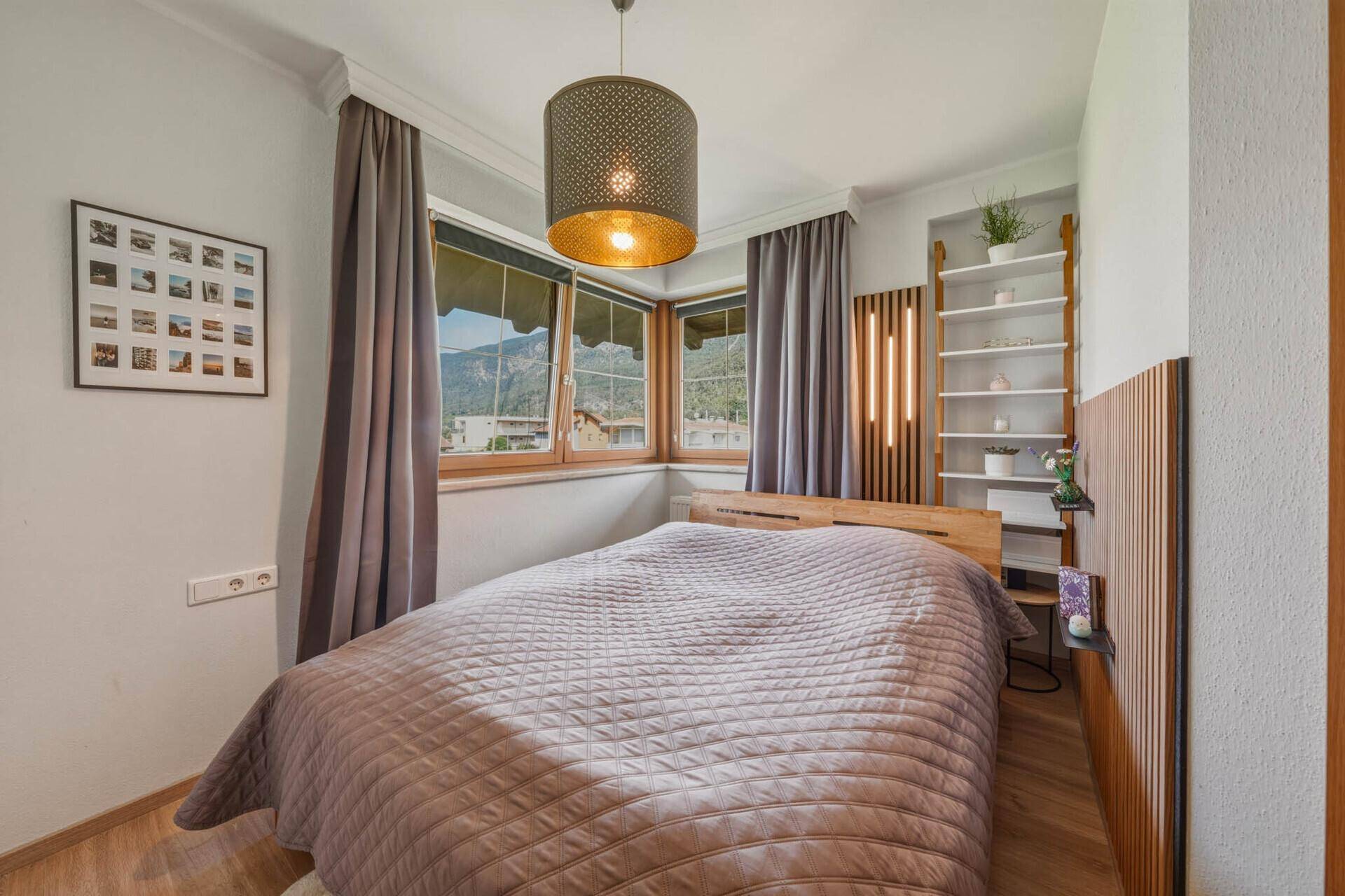 Helles Schlafzimmer mit Holzboden, Doppelbett und dekorativer Wandverkleidung aus Holzlatten.