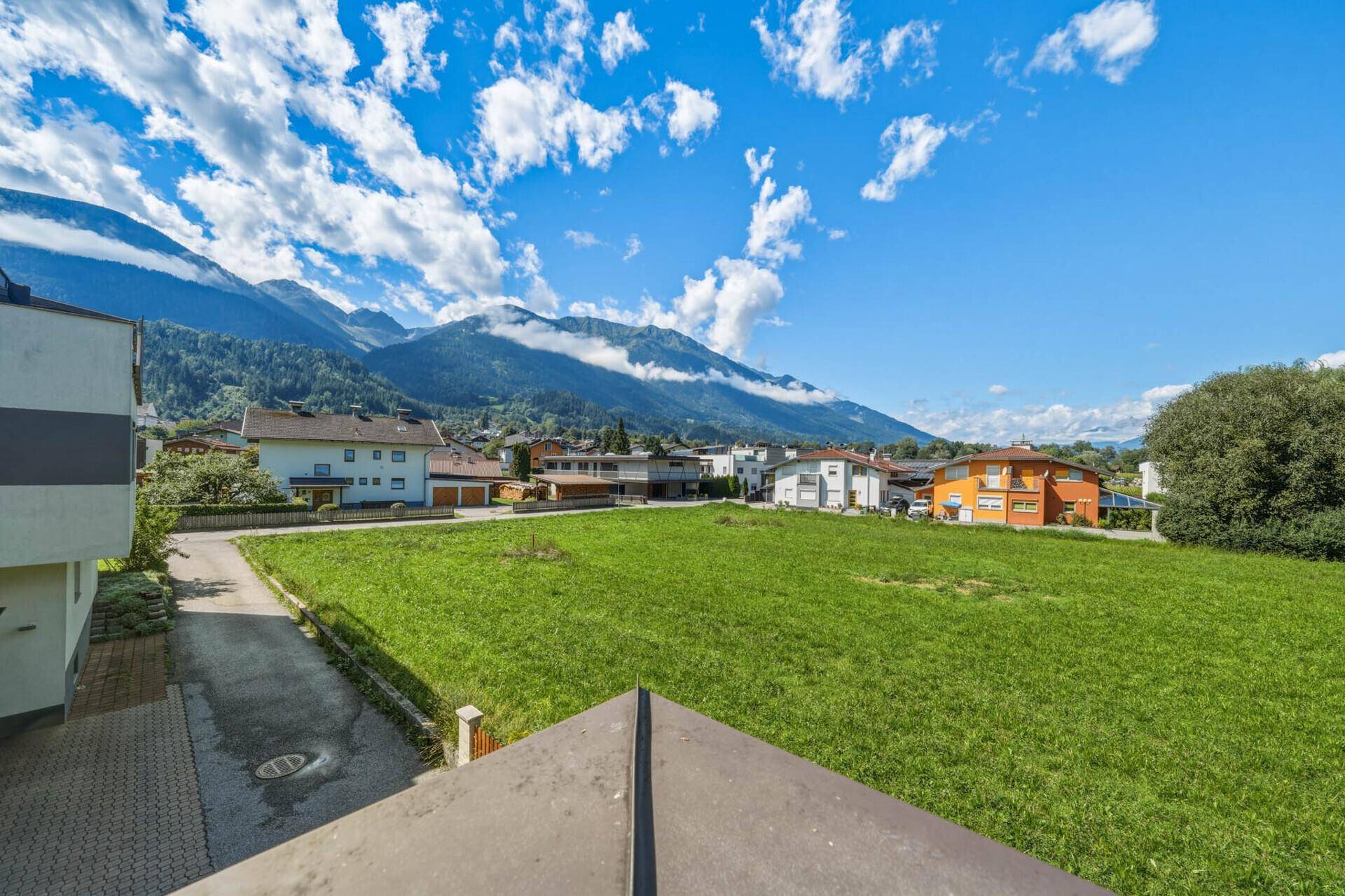 Weitläufige grüne Wiese mit Bergblick unter blauem Himmel.