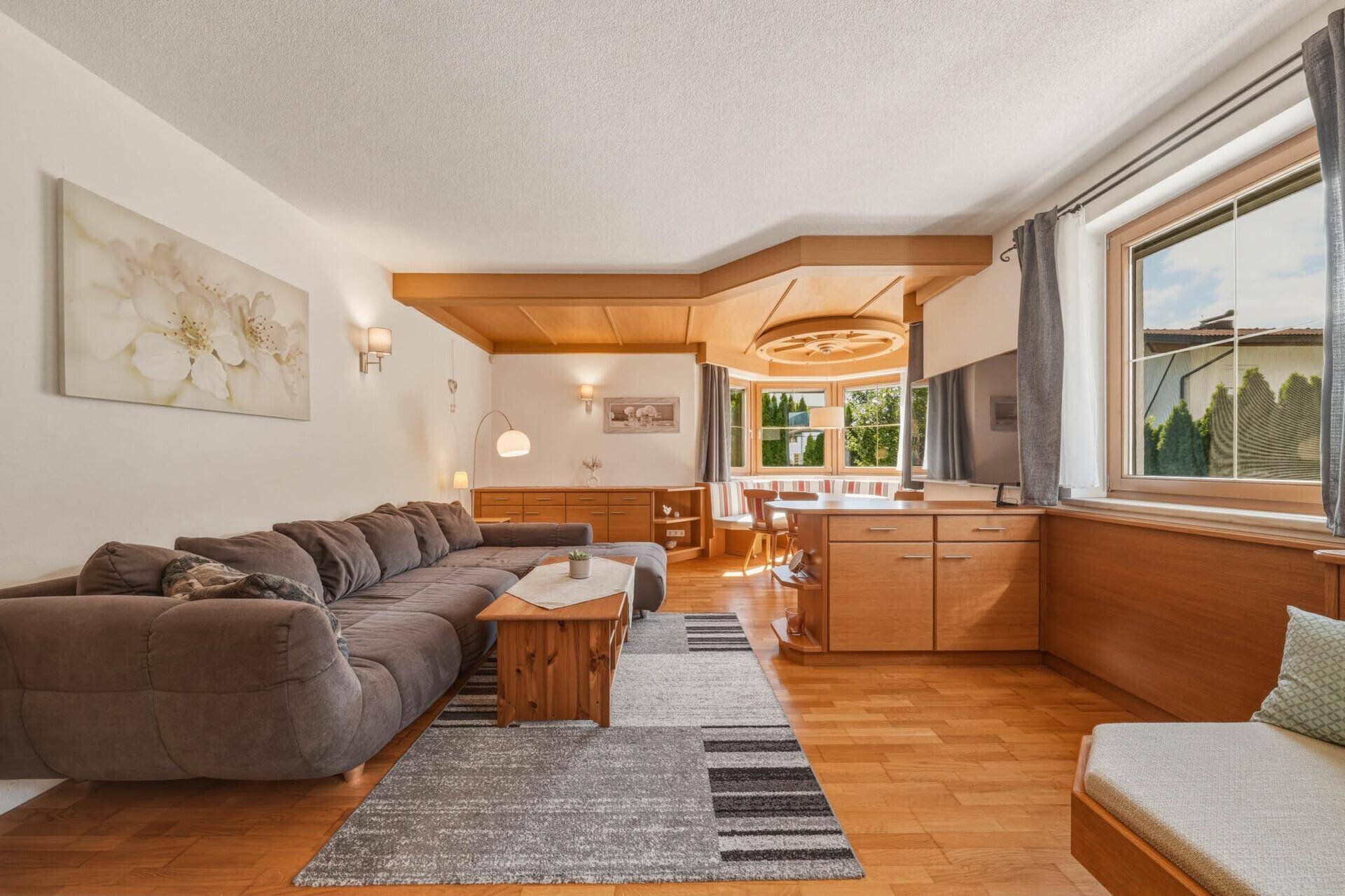 Gemütliches Wohnzimmer mit großem Ecksofa, Holzboden und traditioneller Essecke.