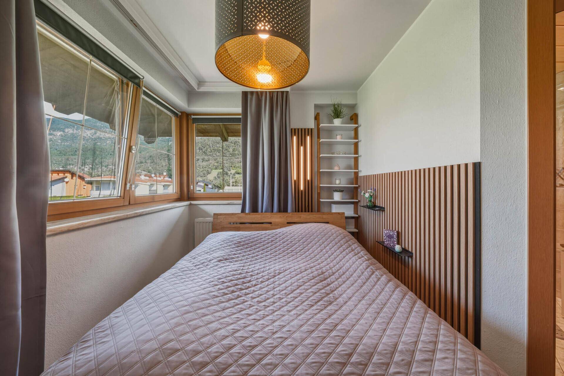 Schlafzimmer mit Holzboden, Doppelbett und einem Regal an der Wand, das Stauraum bietet.