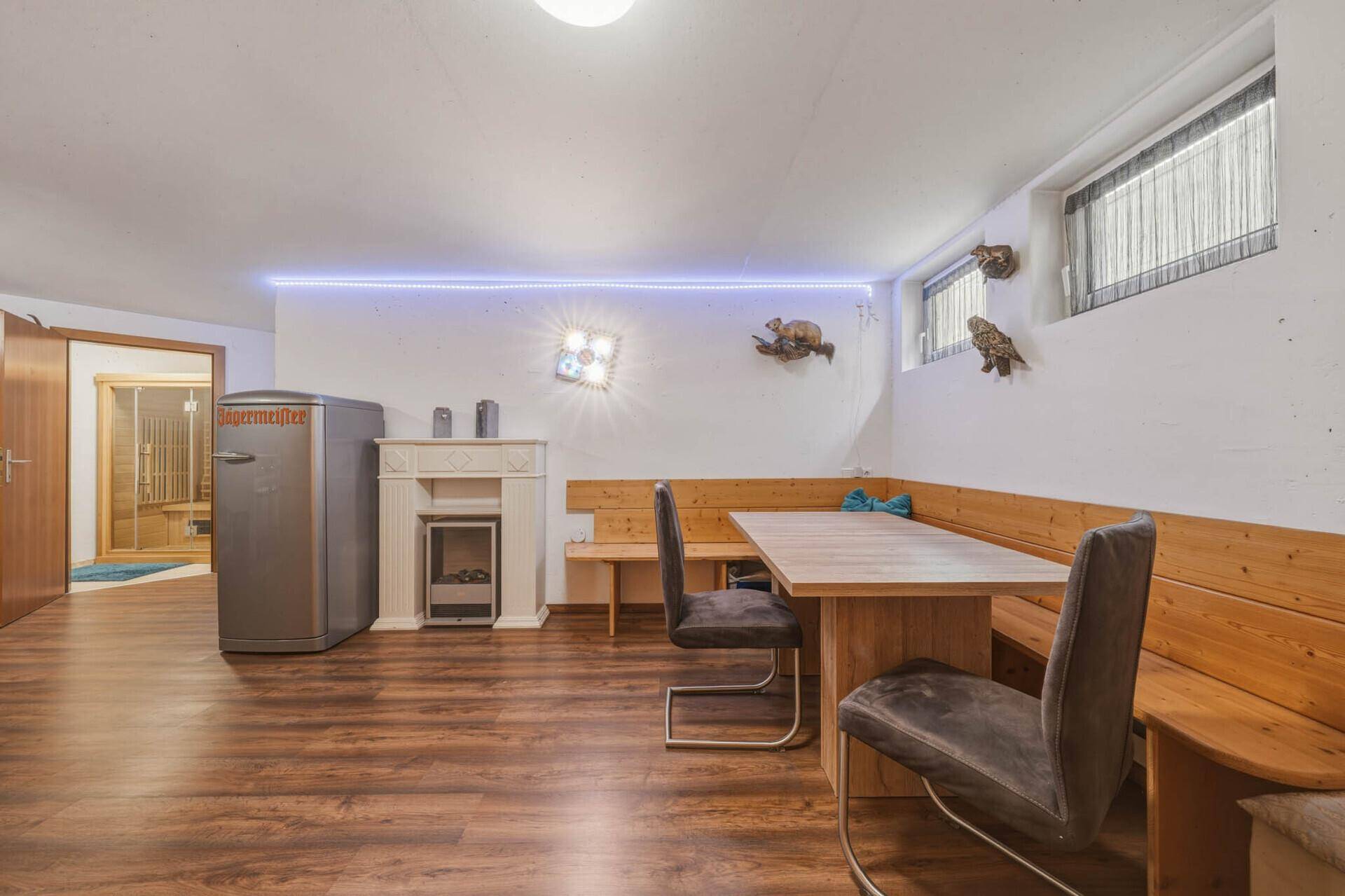 Gemütlicher Bereich im Untergeschoss mit Holzboden, Eckbank und einem kleinen Kamin für Wärme.