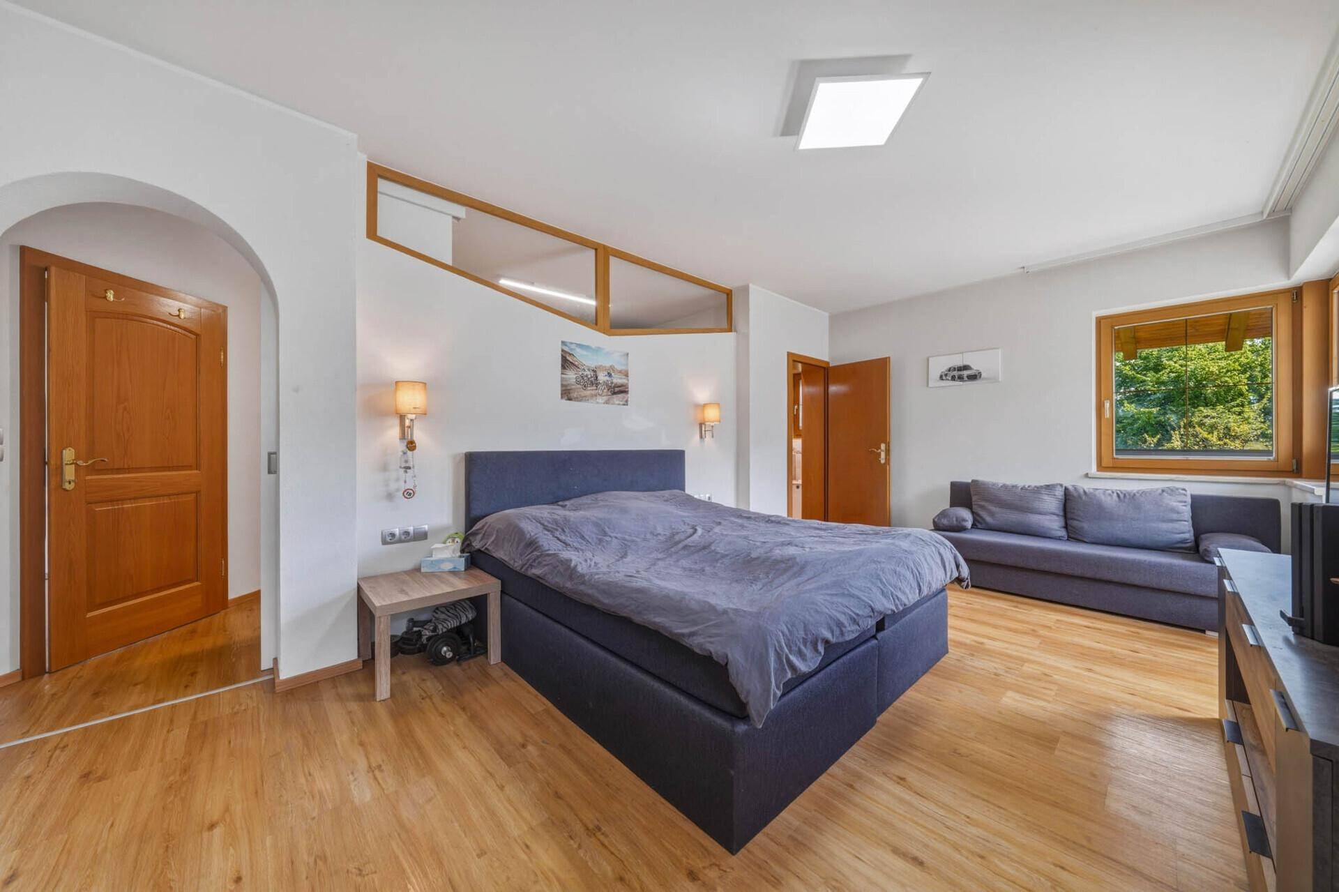 Helles Schlafzimmer mit Doppelbett und Zugang zu weiteren Räumen.