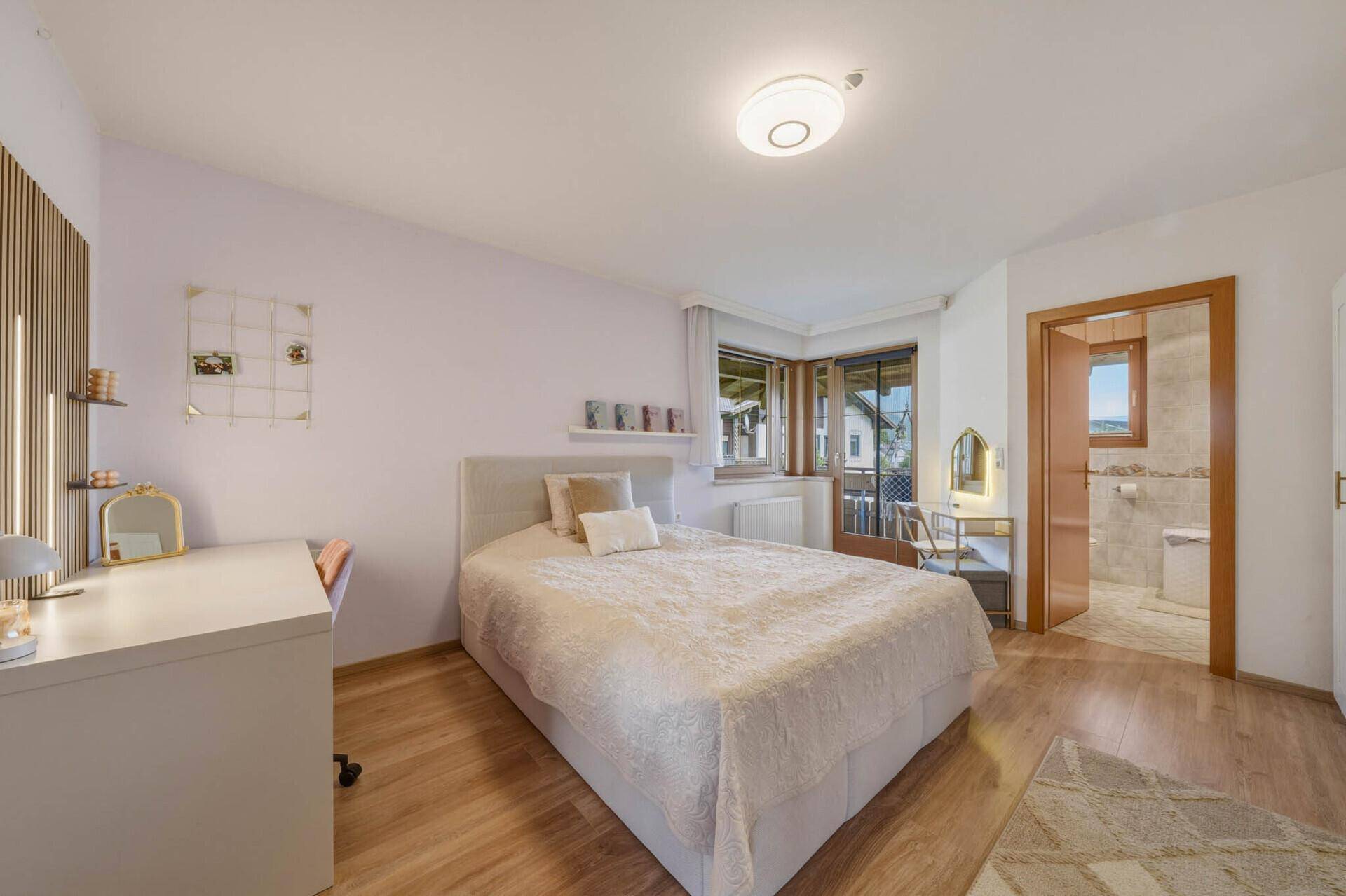 Gemütliches Schlafzimmer mit Doppelbett, Schreibtisch und Zugang zum Badezimmer.