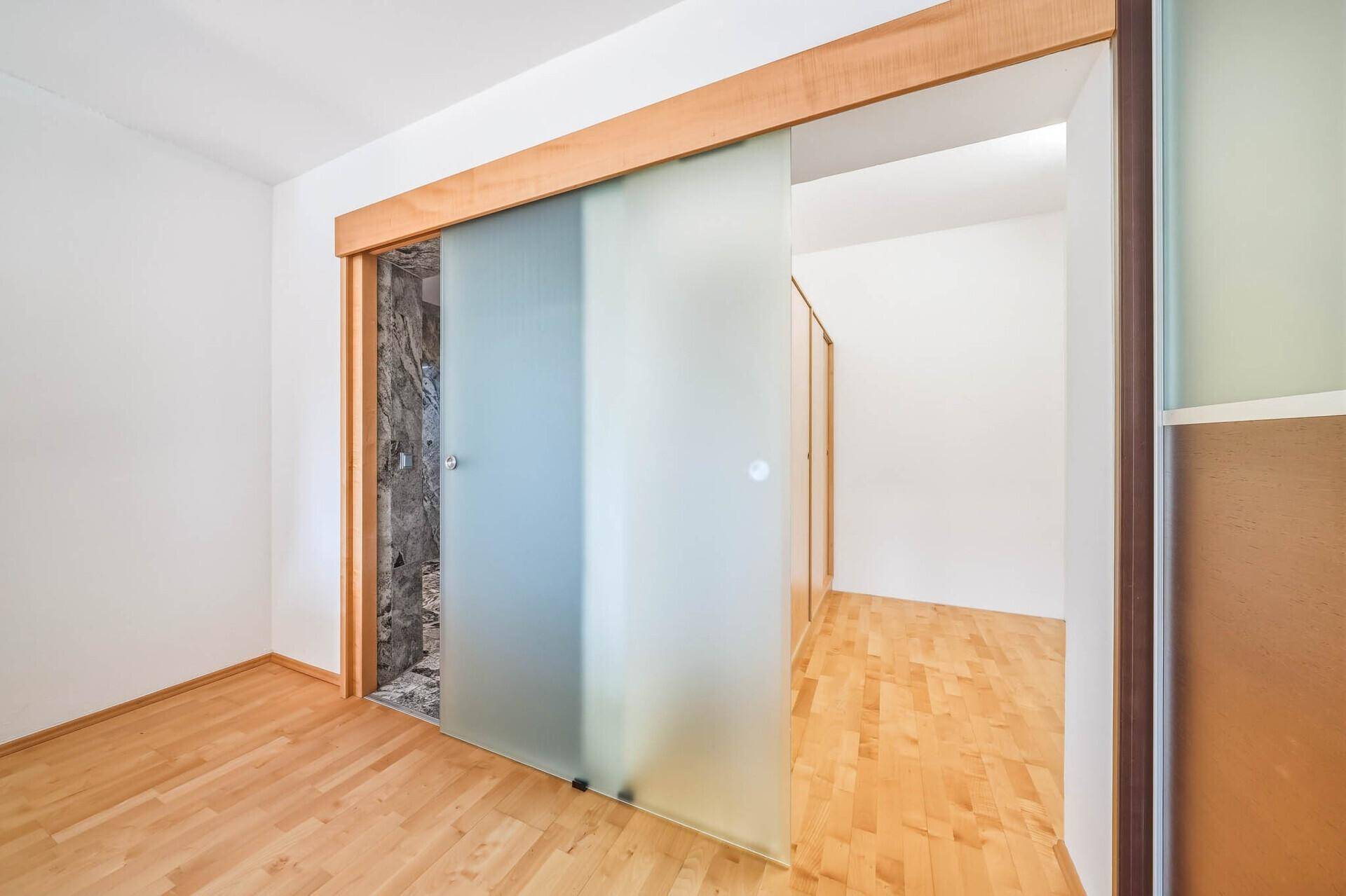 Heller Flur mit Holzboden und moderner Schiebetür aus Milchglas.