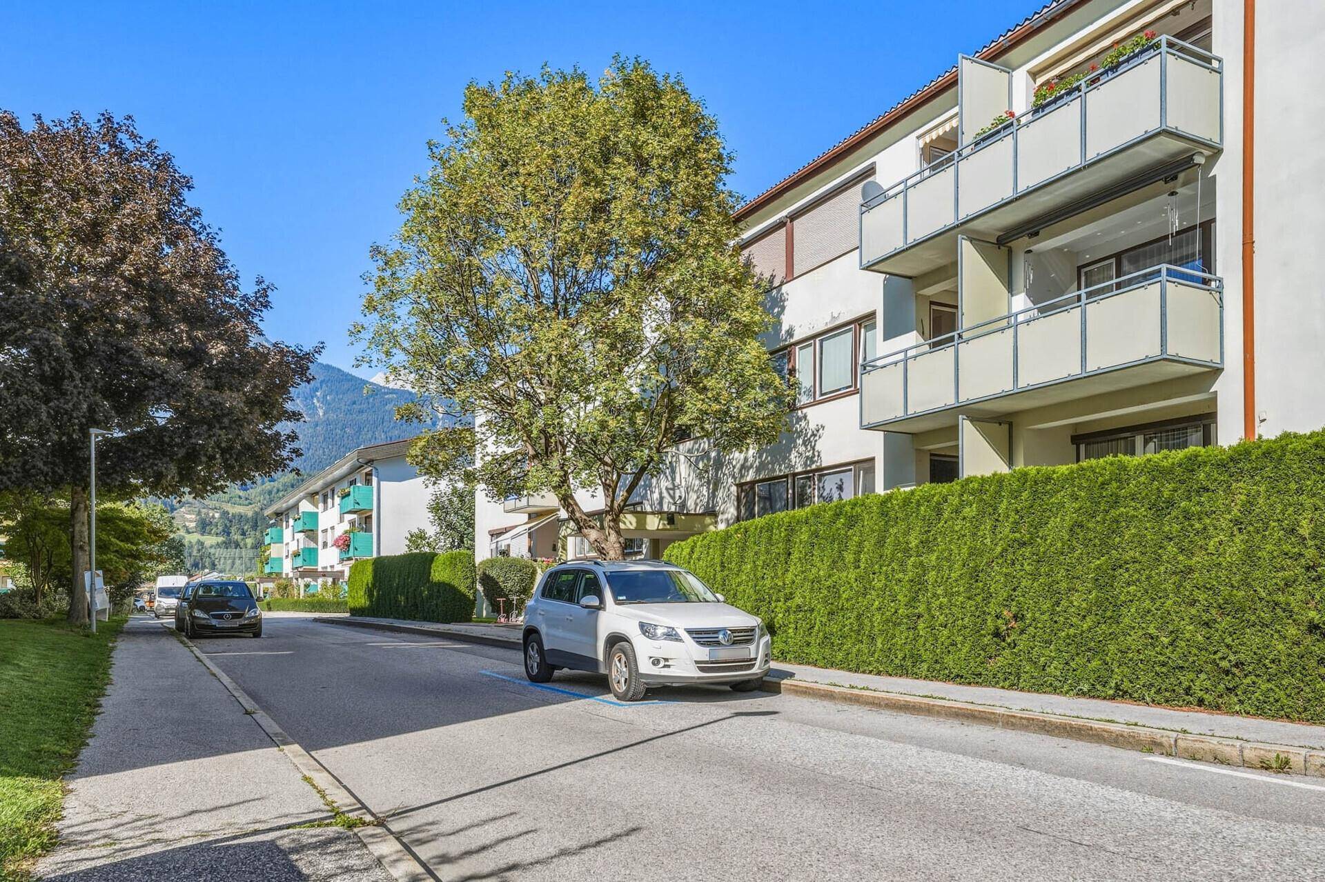 Wohngebäude an einer ruhigen Straße mit Bäumen und gepflegten Grünflächen.